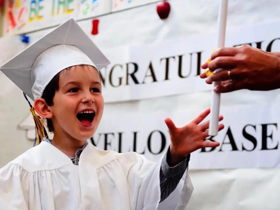 The author's son wearing a white graduation gown and cap.