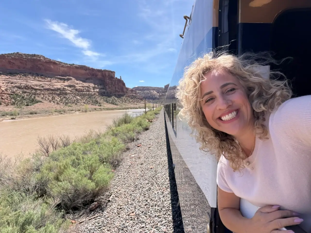 The author smiling from the window of a train while traveling.