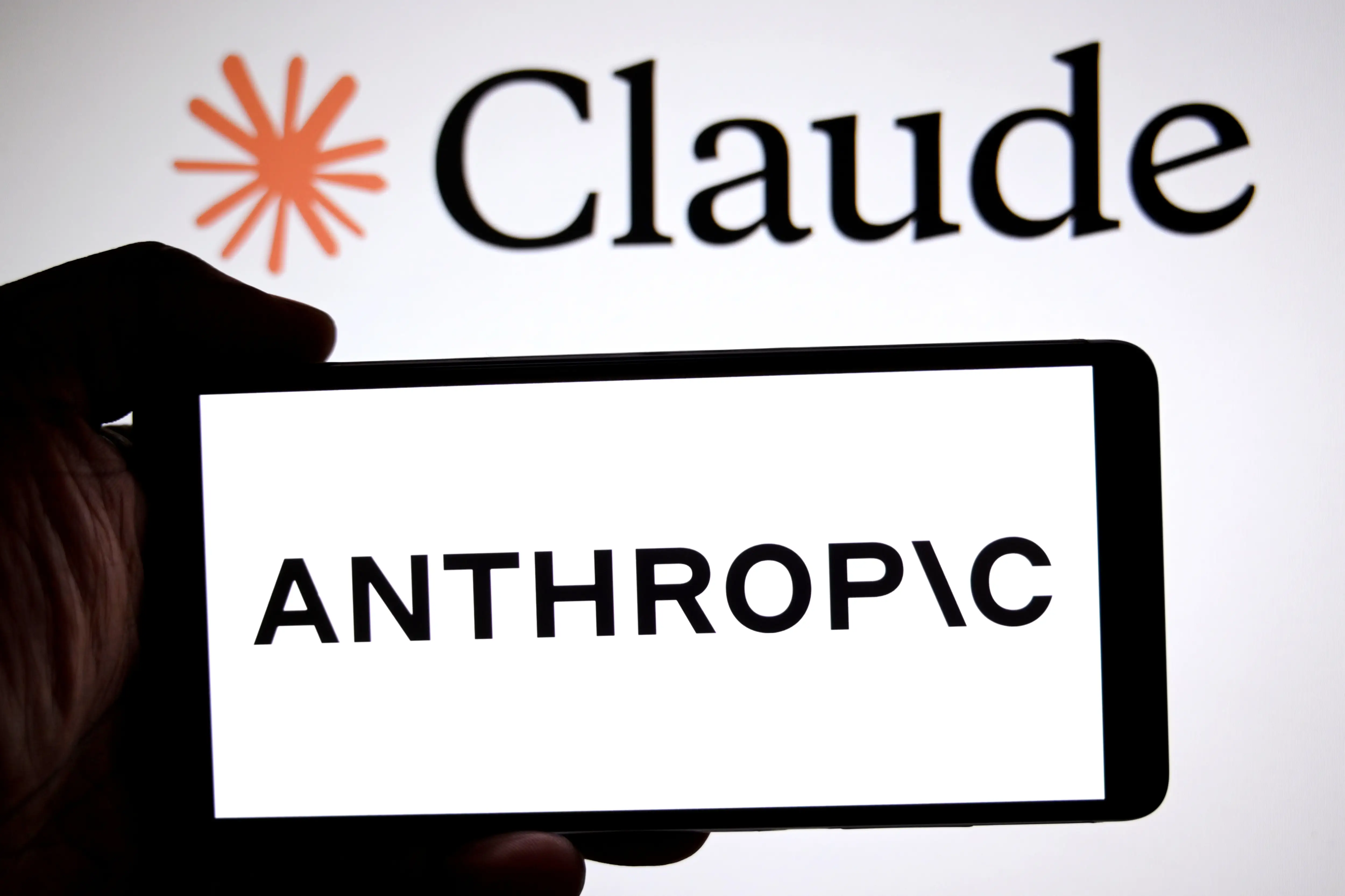 In this photo illustration, an Anthropic logo is seen displayed on a smartphone with a Claude mythos logo in the background.