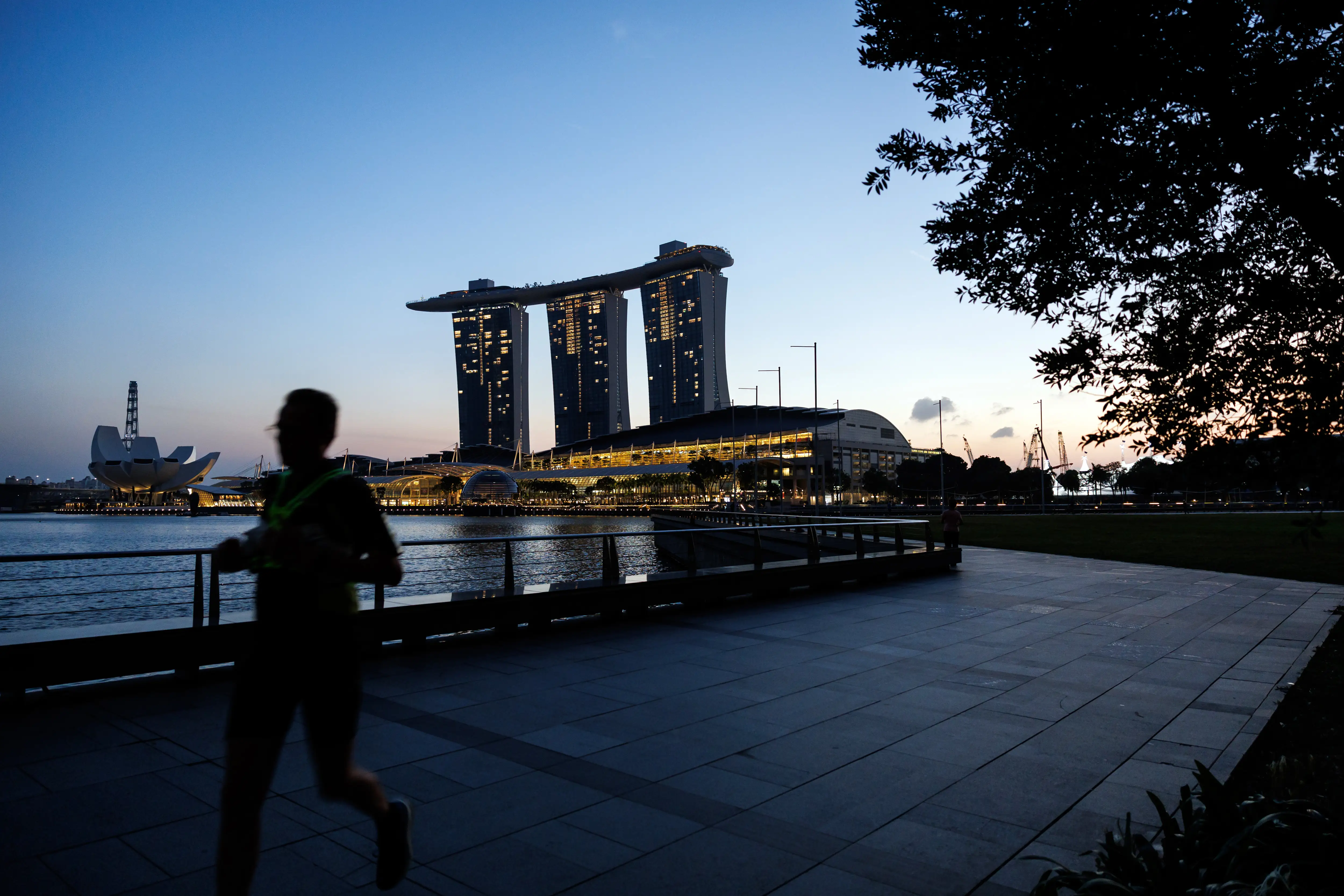 Runner on a waterfront path in front of Singapore's iconic Marina Bay Sands building