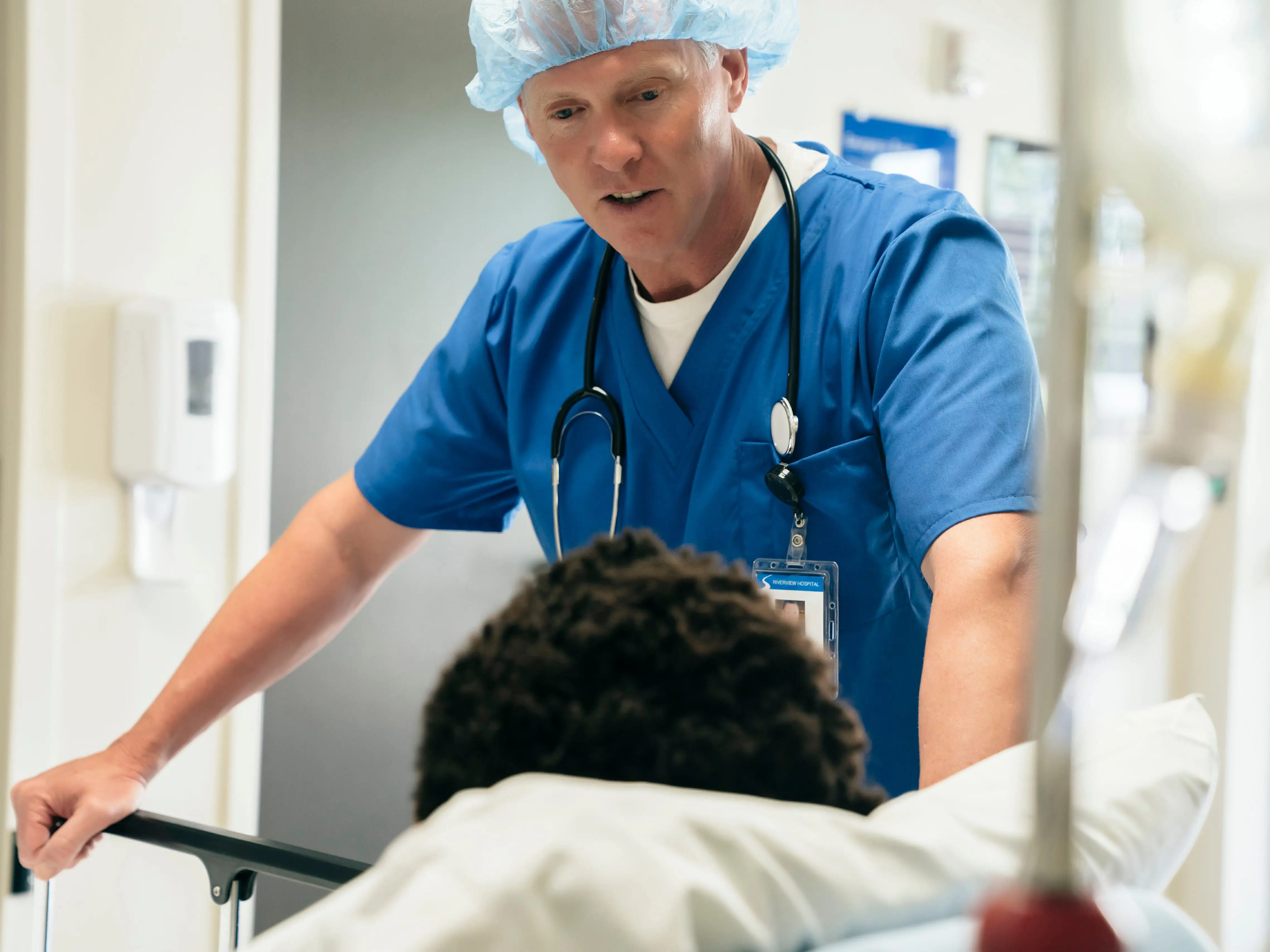 A healthcare worker talking to a patient who is in a hospital bed