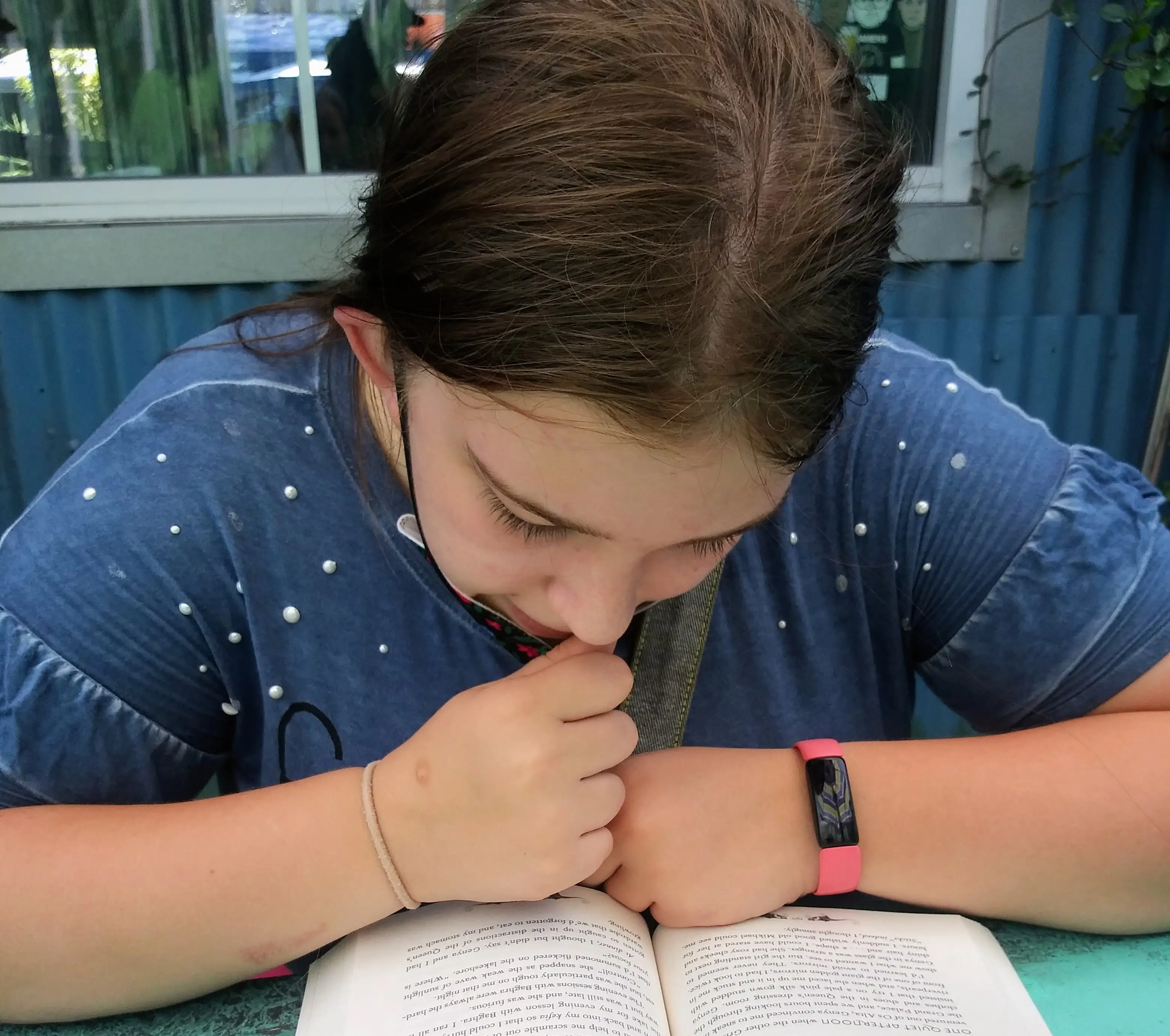 The author's daughter reads while sitting with her mom at a bar.