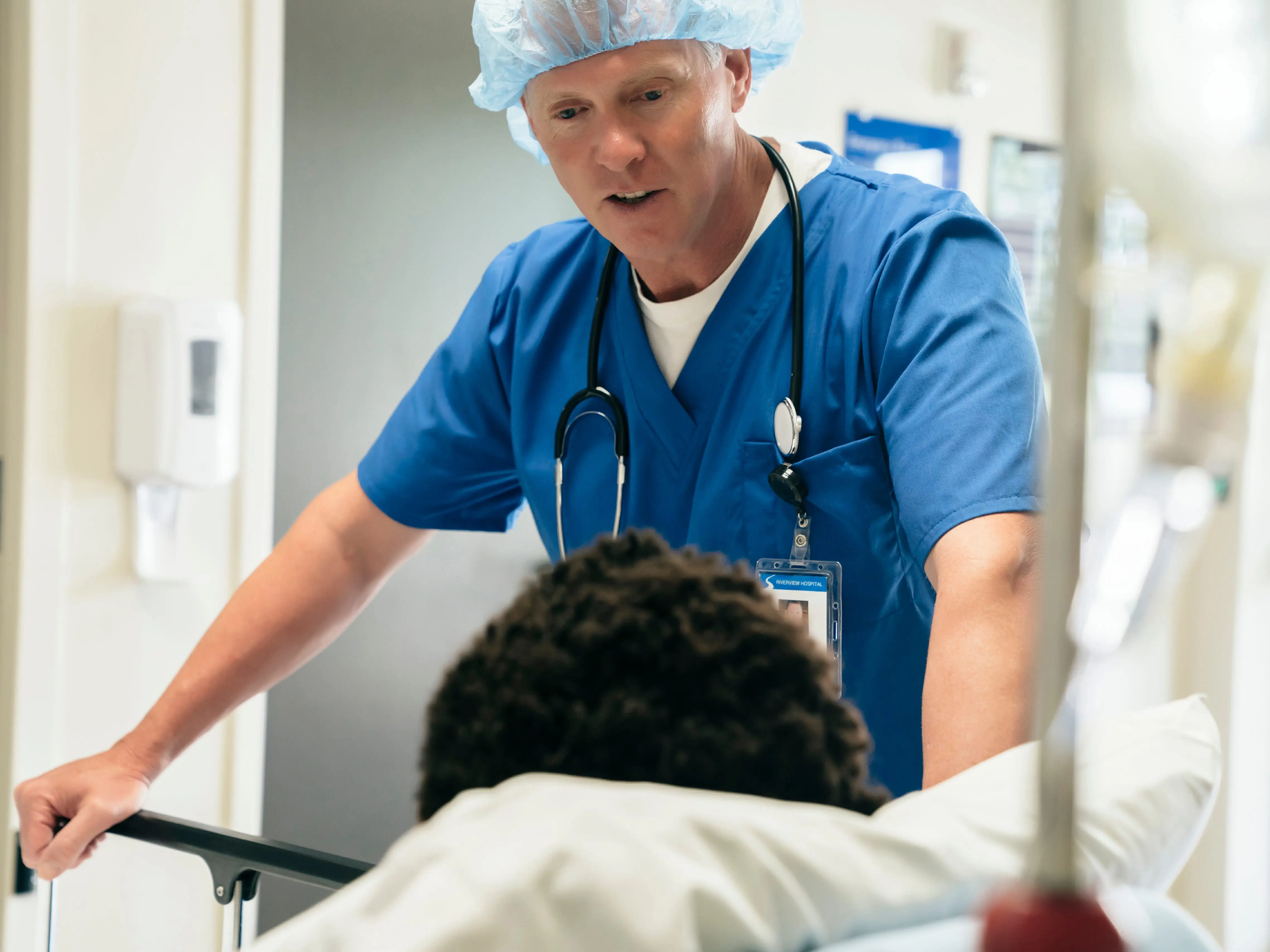 A healthcare worker talking to a patient who is in a hospital bed