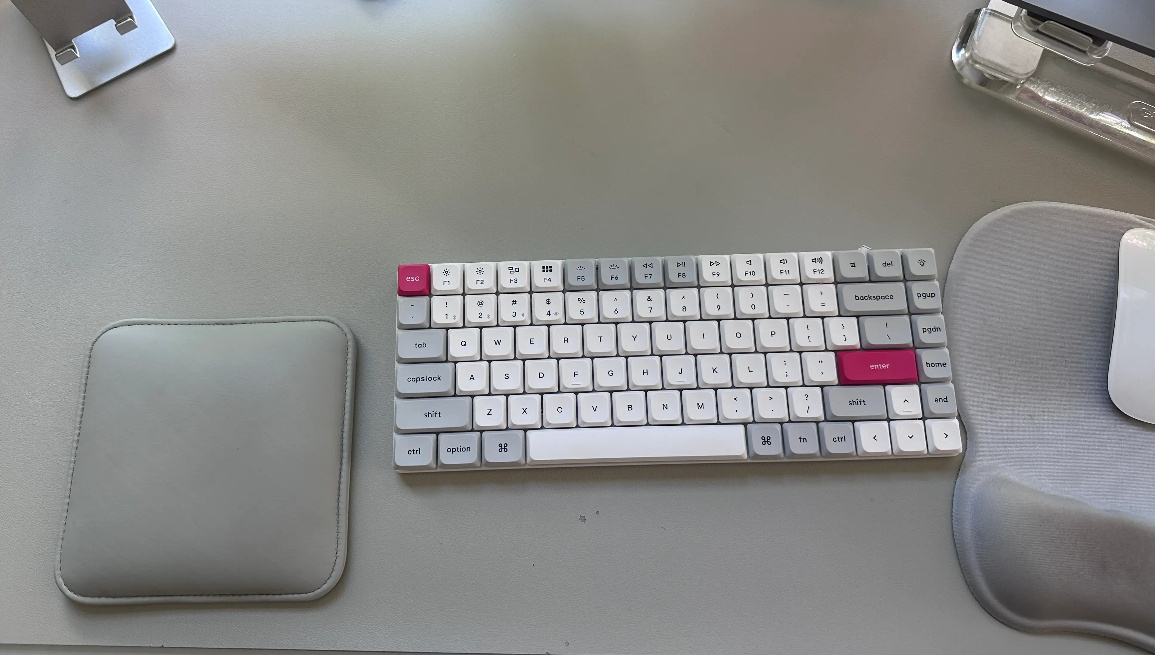 Keyboard on a home office desk, with an elbow pad to the left and a mouse to the right.