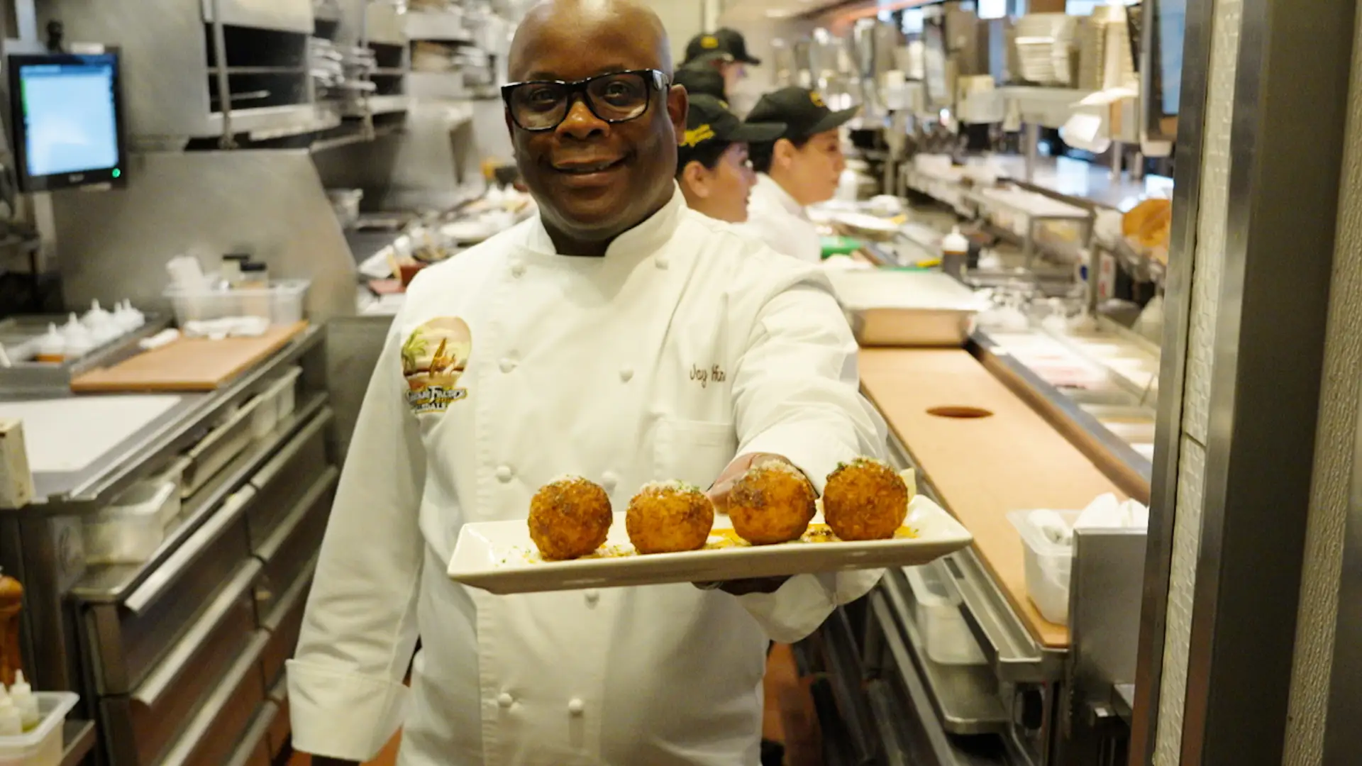 Jay in The Cheesecake Factory kitchen holding an appetizer.