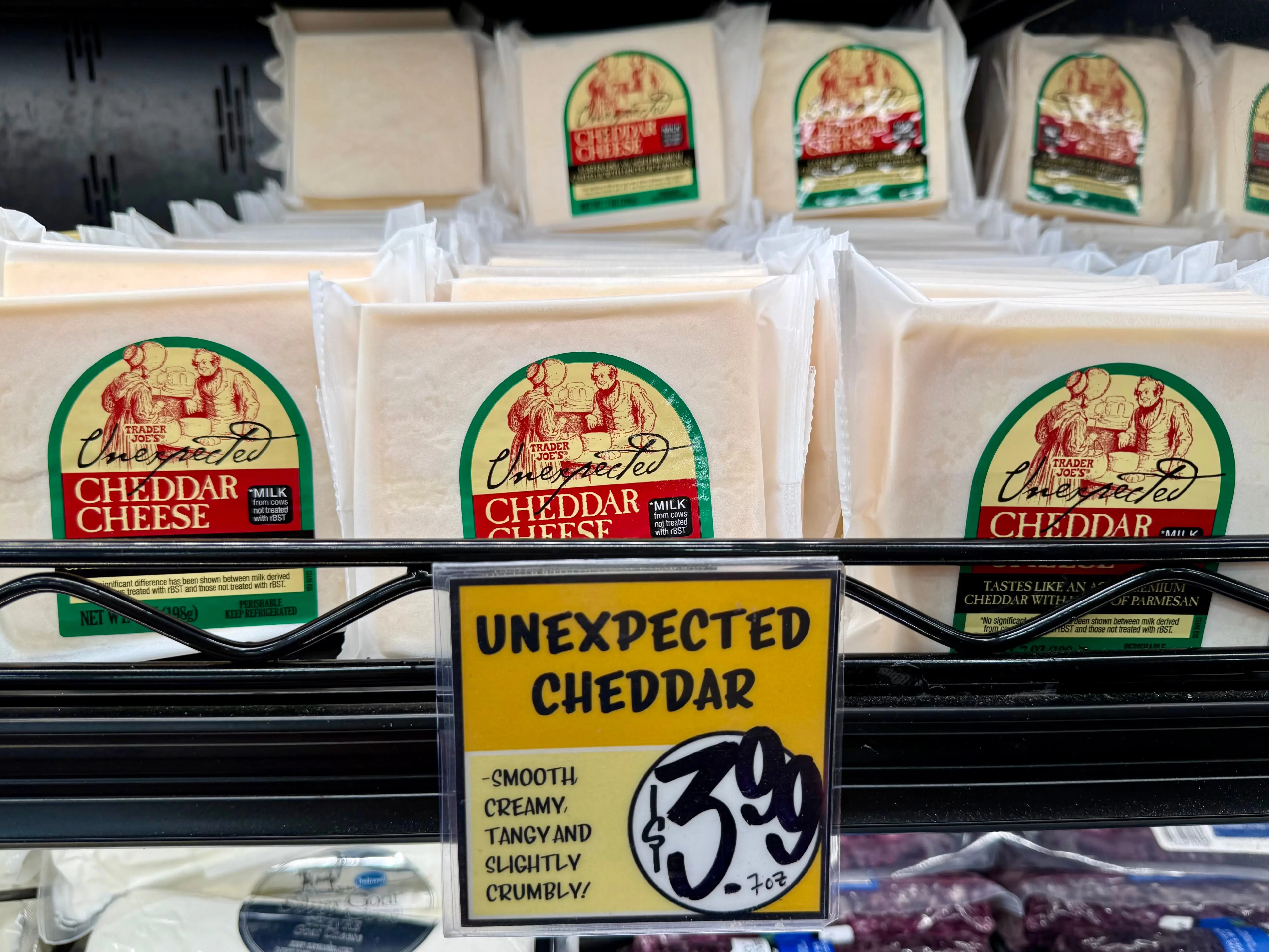 Several packages of Trader Joe's Unexpected cheddar sit on a shelf.