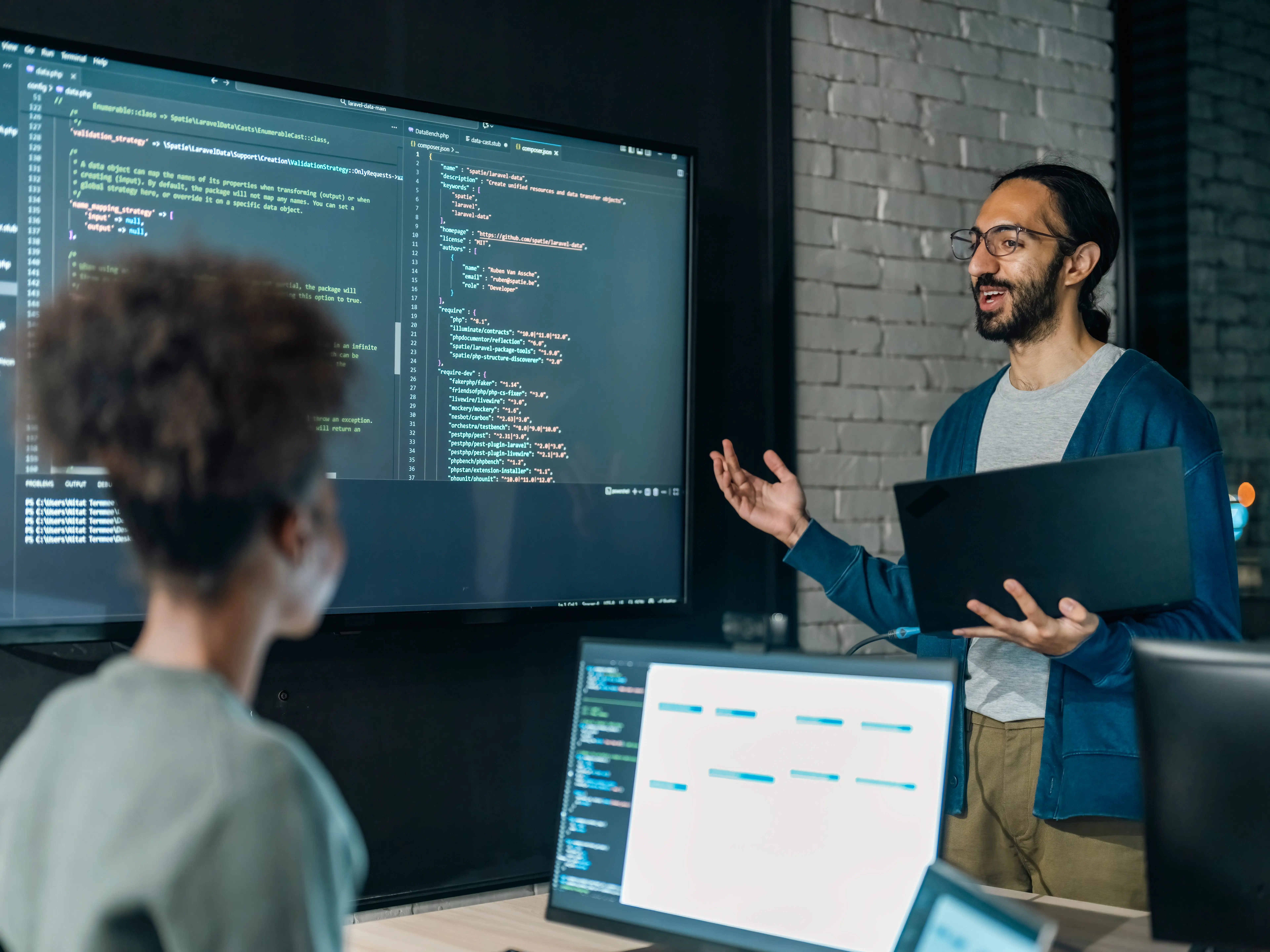 People in tech working in an office with code on a large screen