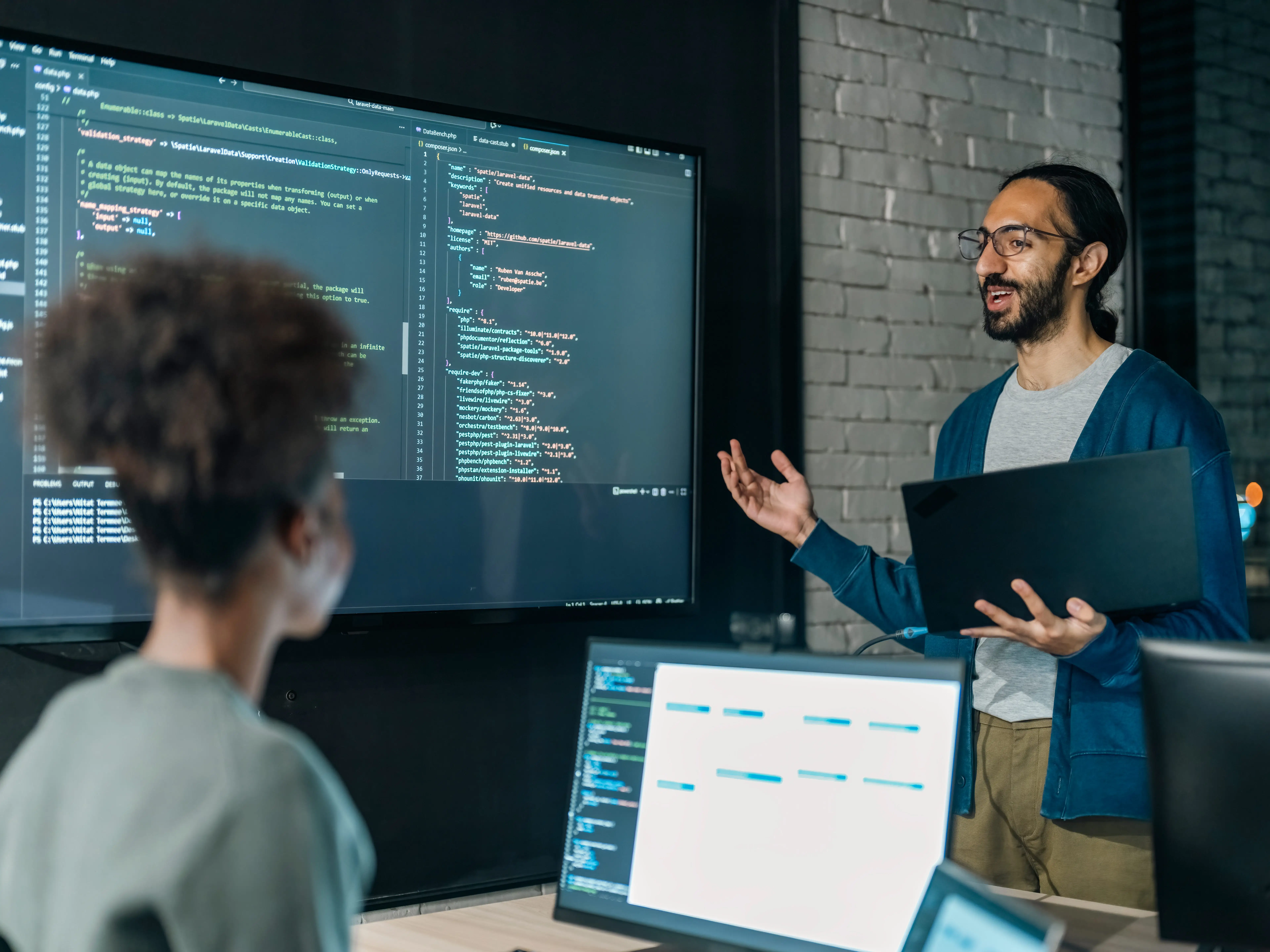 People in tech working in an office with code on a large screen