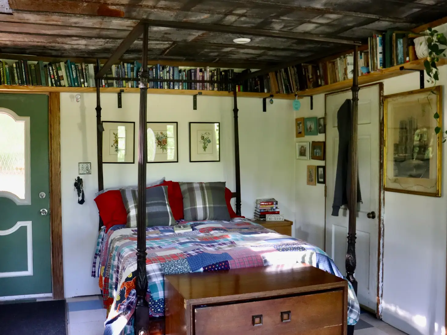 The writer's bedroom in her cabin, with a green door and lots of shelving for books.