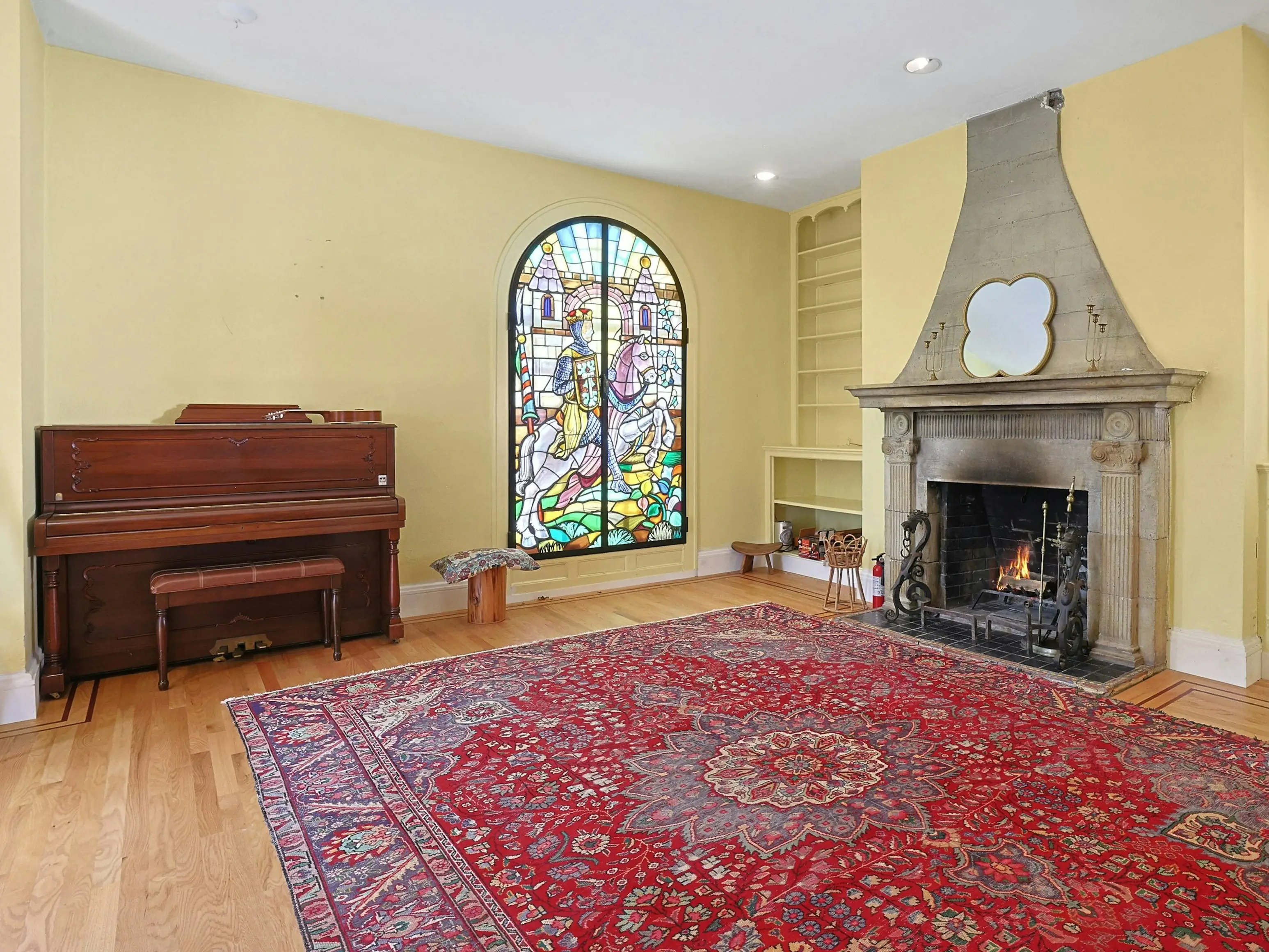 Upright piano, stained glass with medieval design and a fireplace in the living room