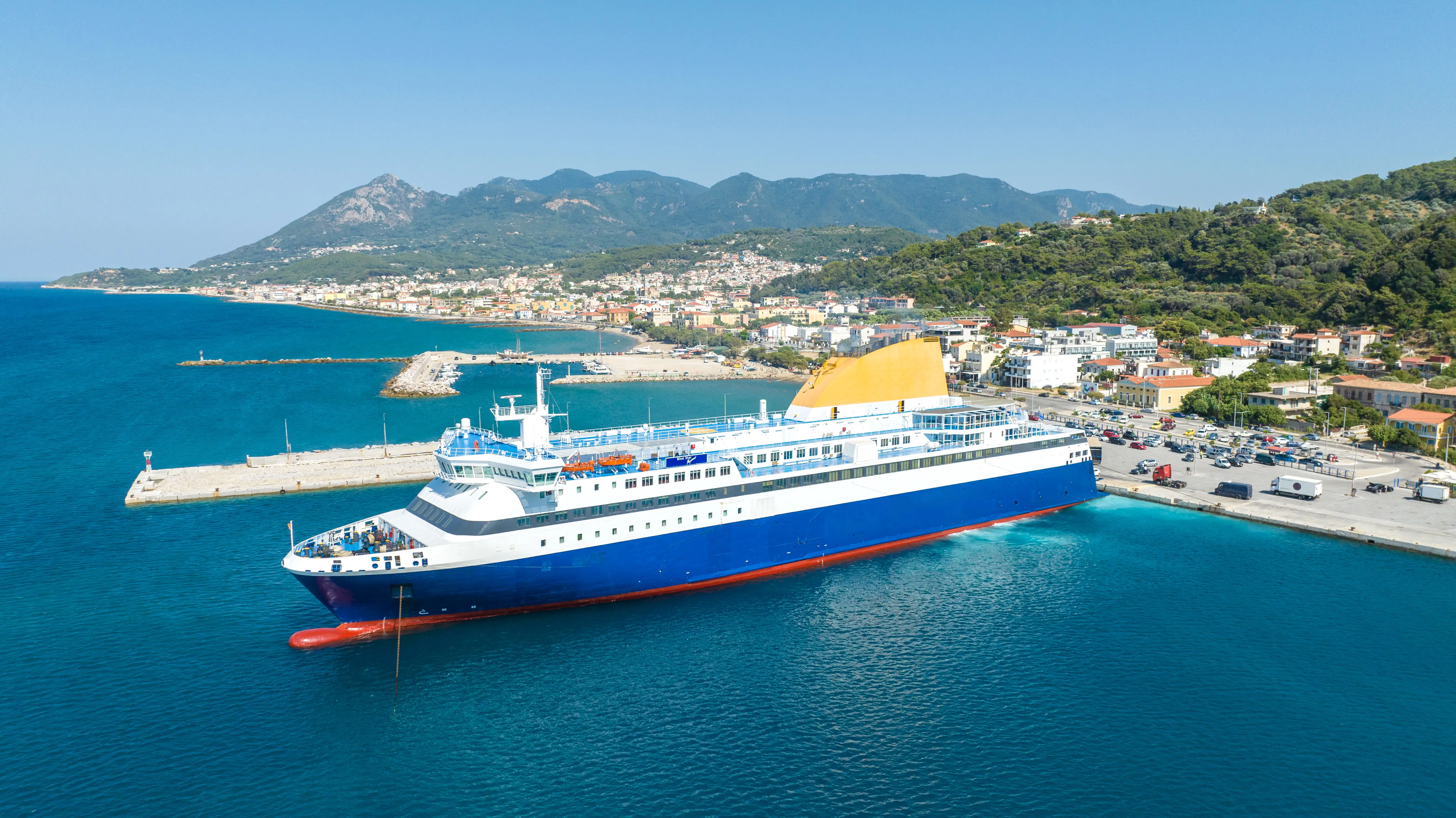 Aerial view of cruise ship docked in blue waters next to island