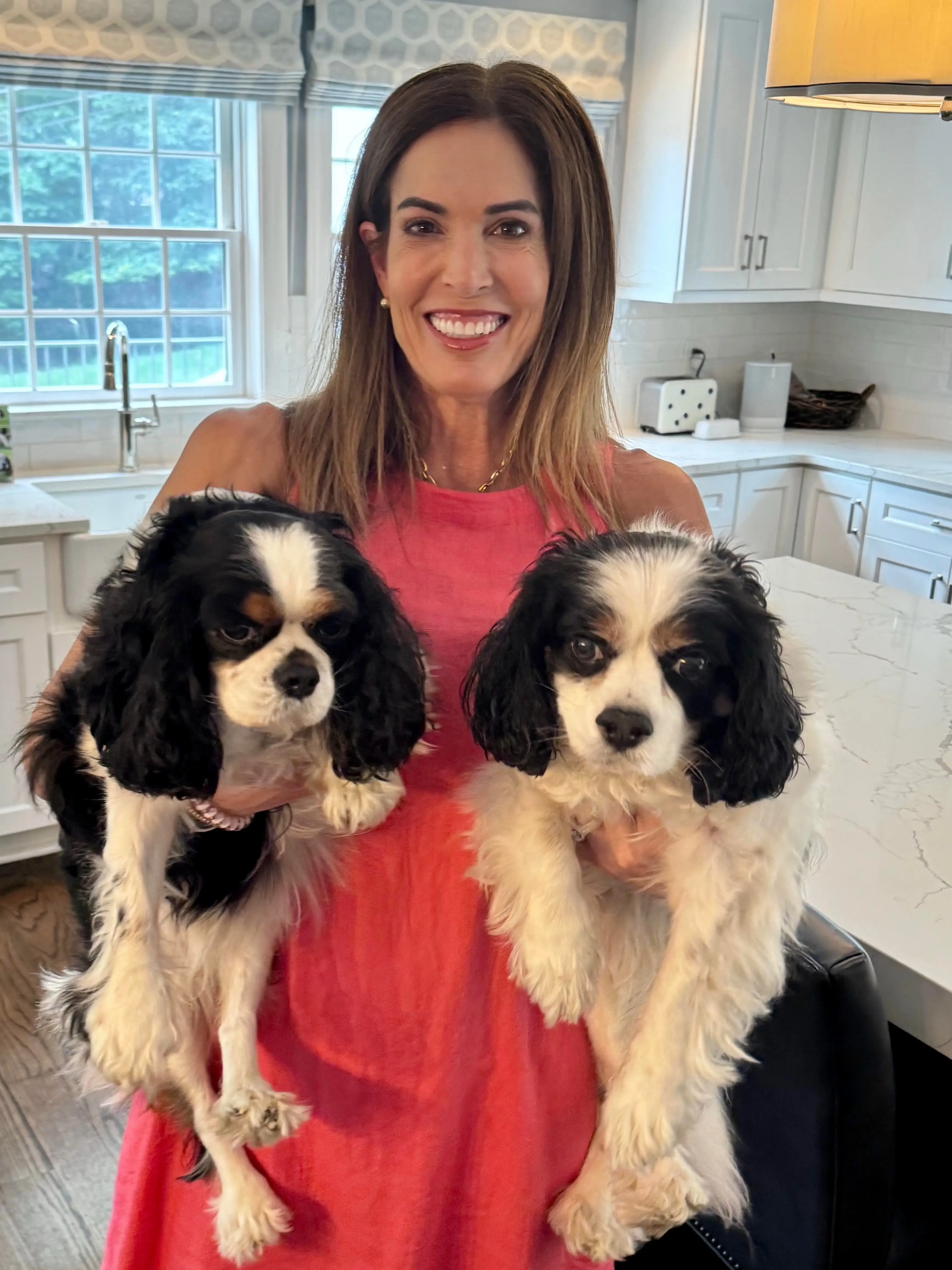 a woman holds two dogs in her kitchen