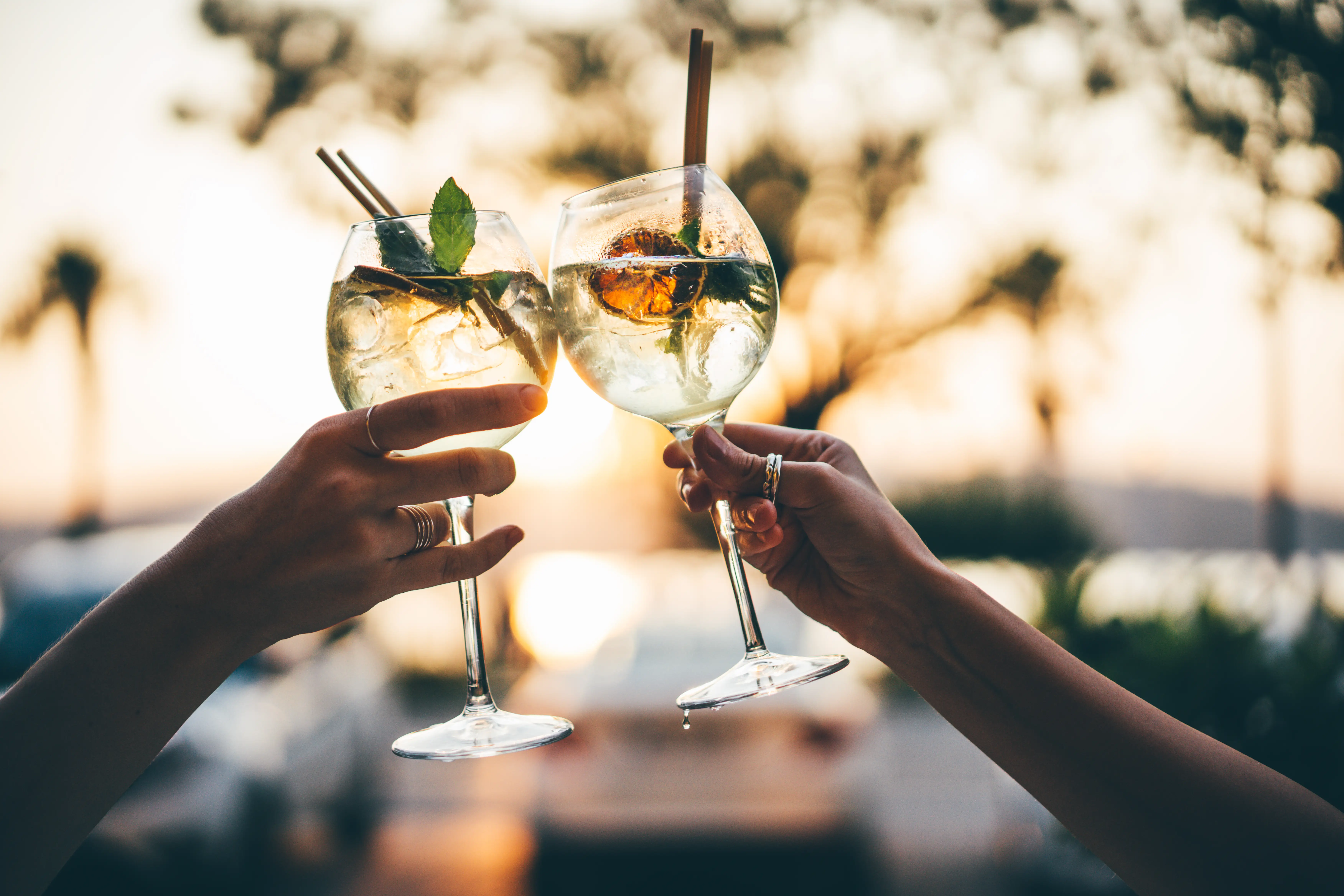 cheers with cocktails on a sunny outside patio
