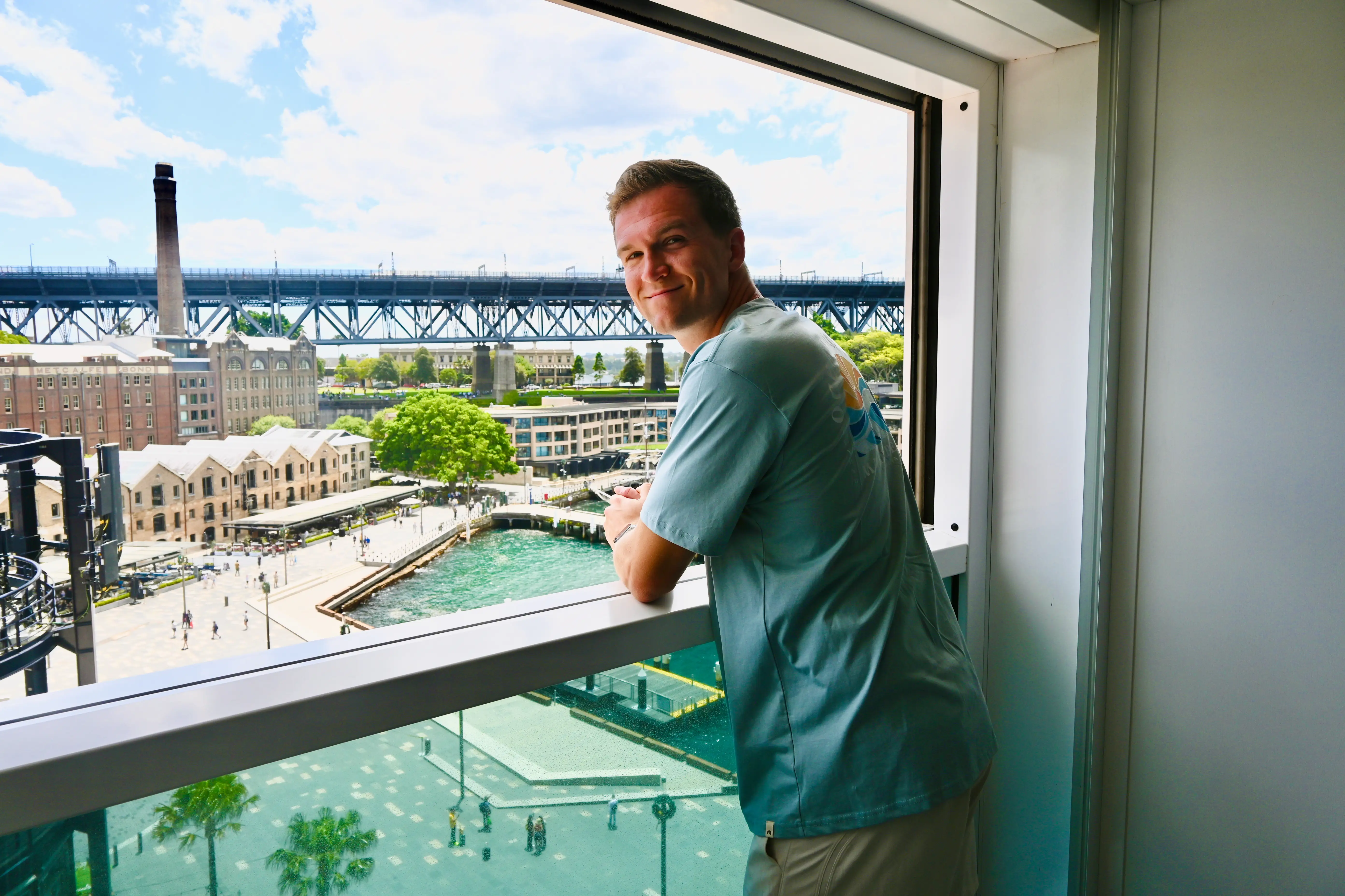 Man leaning over ledge of window in  Infinite Veranda cabin on Celebrity cruise
