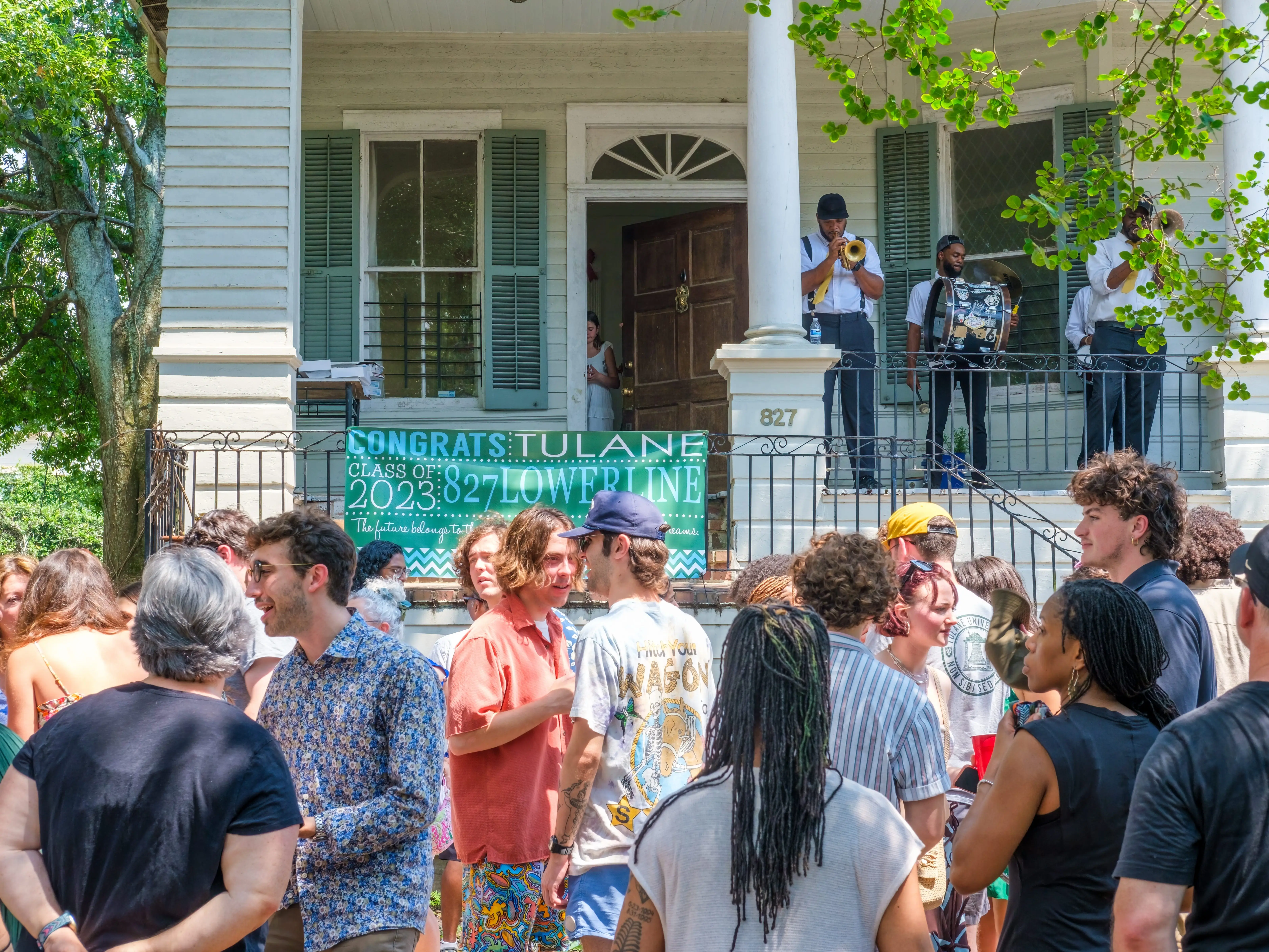 NEW ORLEANS, LA, USA - MAY 20,  2023: Tulane University students celebrate their graduation with a brass band playing on the front porch of an historic Uptown home