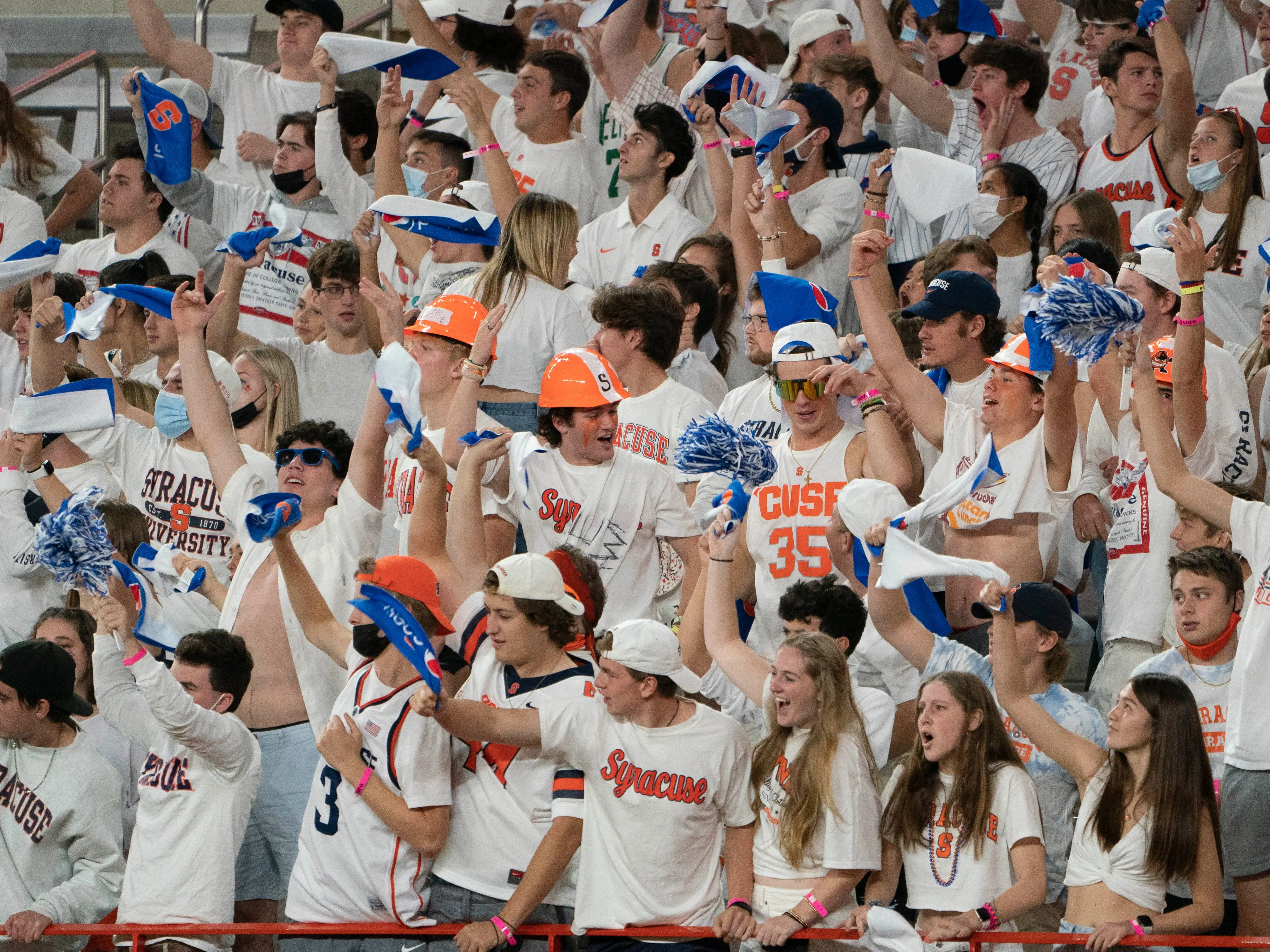 A crowd of Syracuse University students cheering. They're all dressed in white T-shirts with 