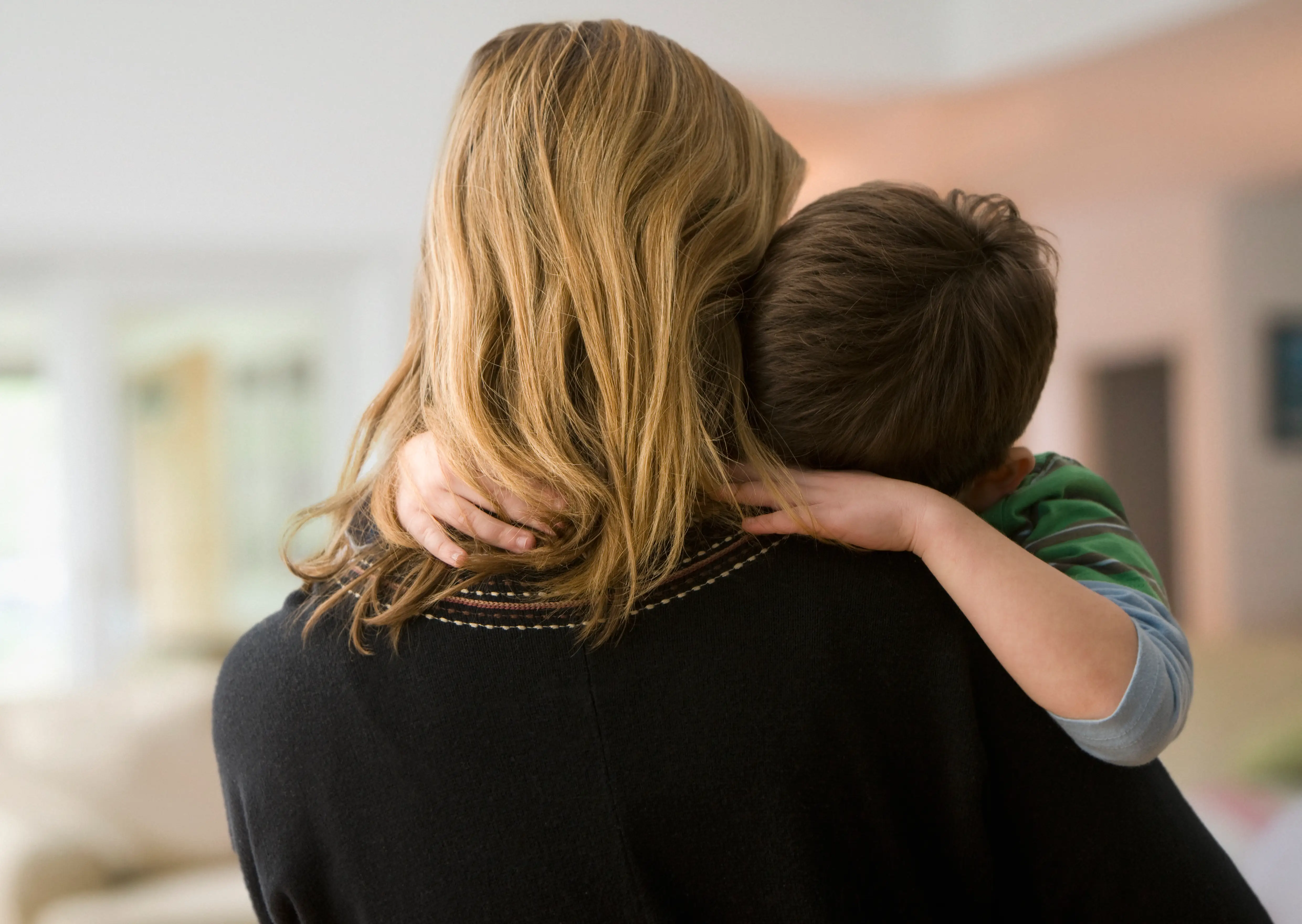 Woman hugging her son, view from behind.