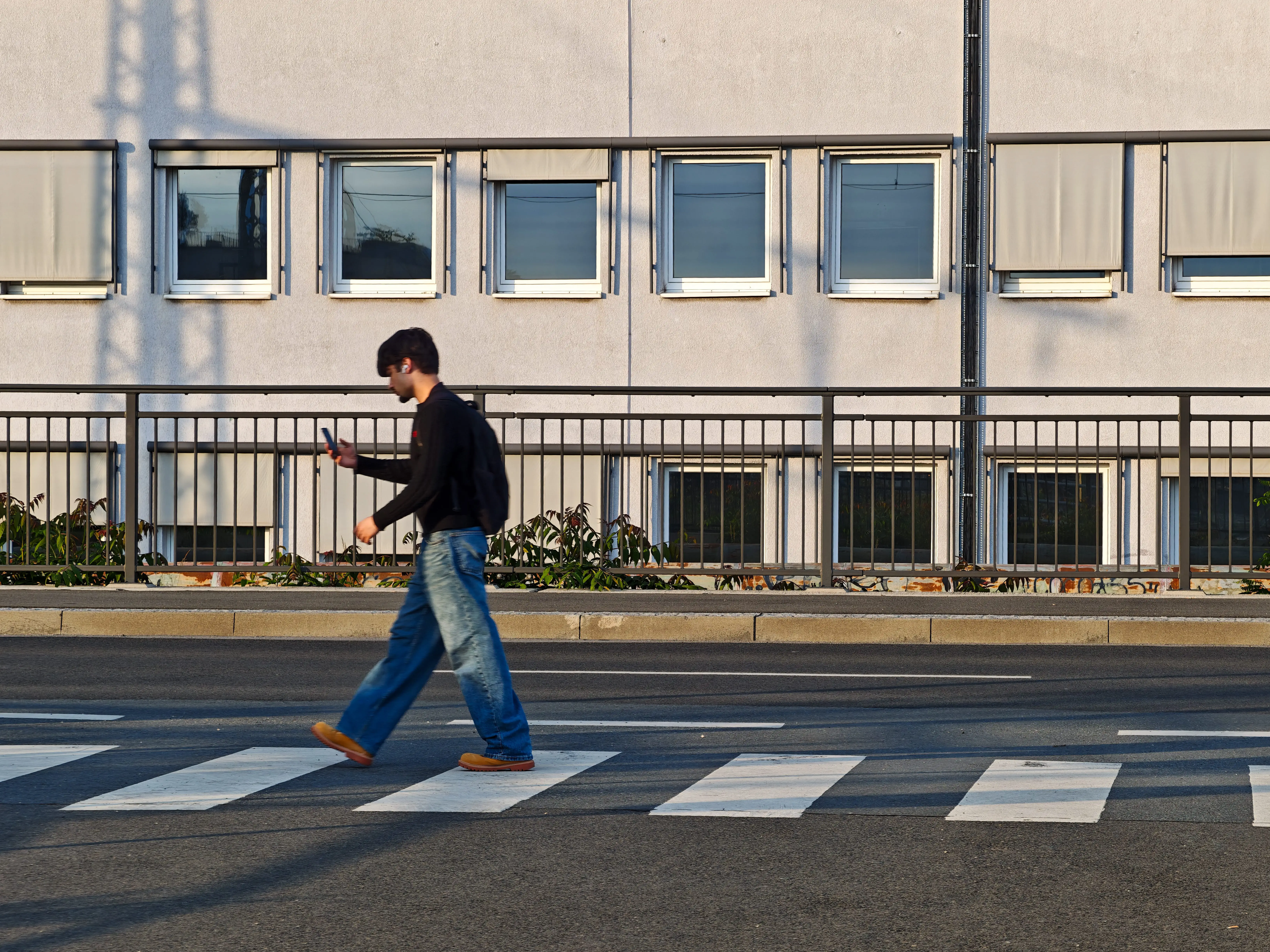A young man uses a smartphone while walking across a zebra crossing in Frankfurt am Main, Hesse, Germany, on May 16, 2026. Smartphones and social media are part of daily communication and digital habits among young people. (Photo by Michael Nguyen/NurPhoto via Getty Images)