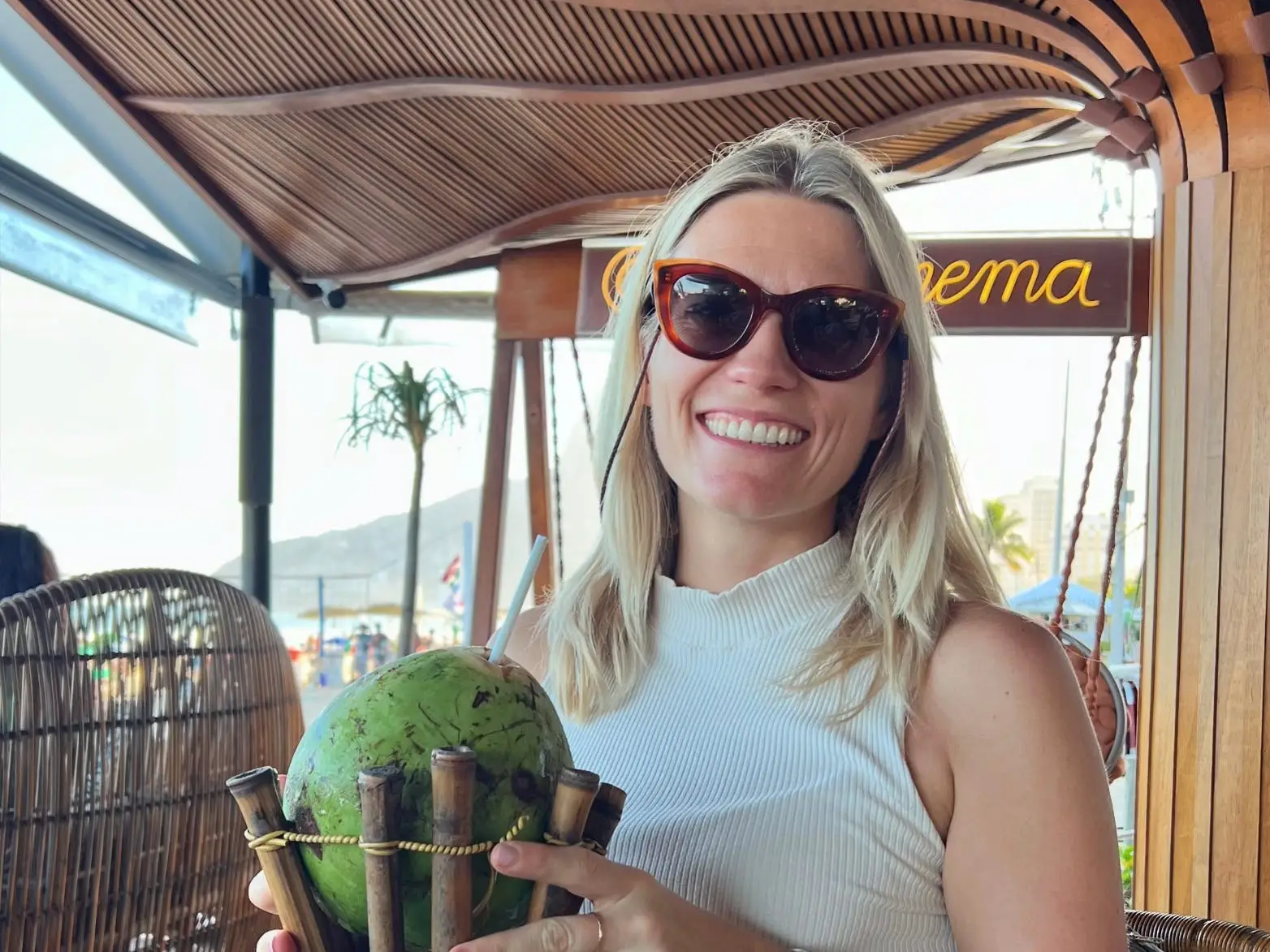 A woman holding a coconut on the beach in Brazil.