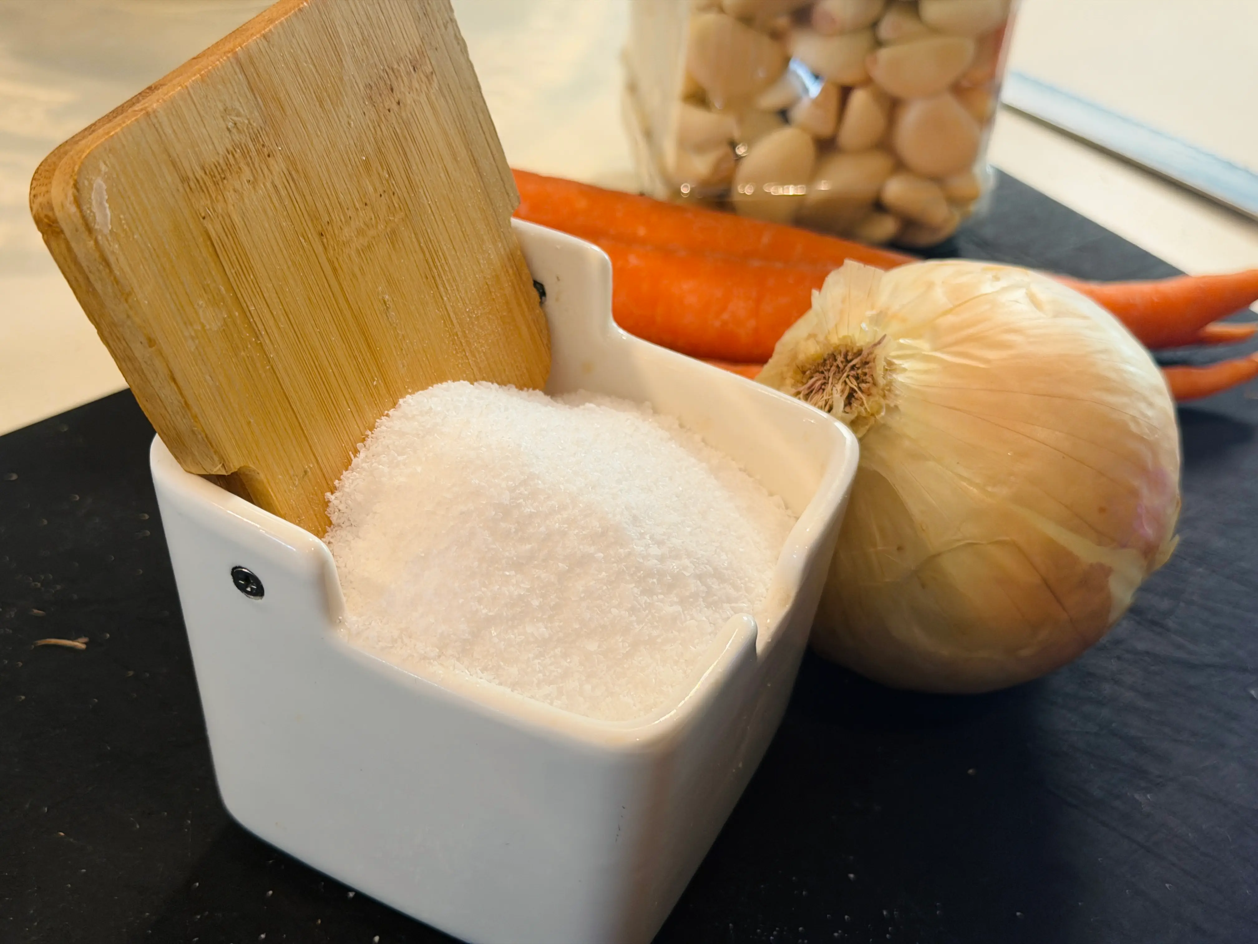 salt bucket with onion and carrots in background