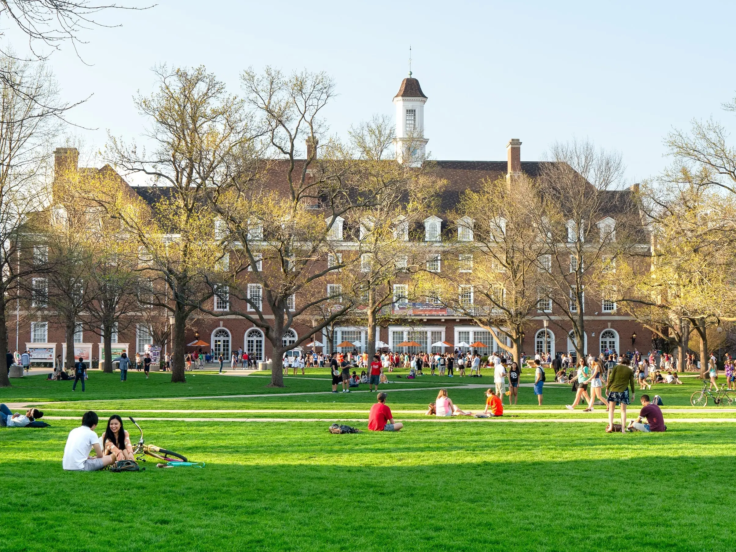 Students sit and walk outside on Quad lawn of University of Illinois college campus in Urbana Champaign