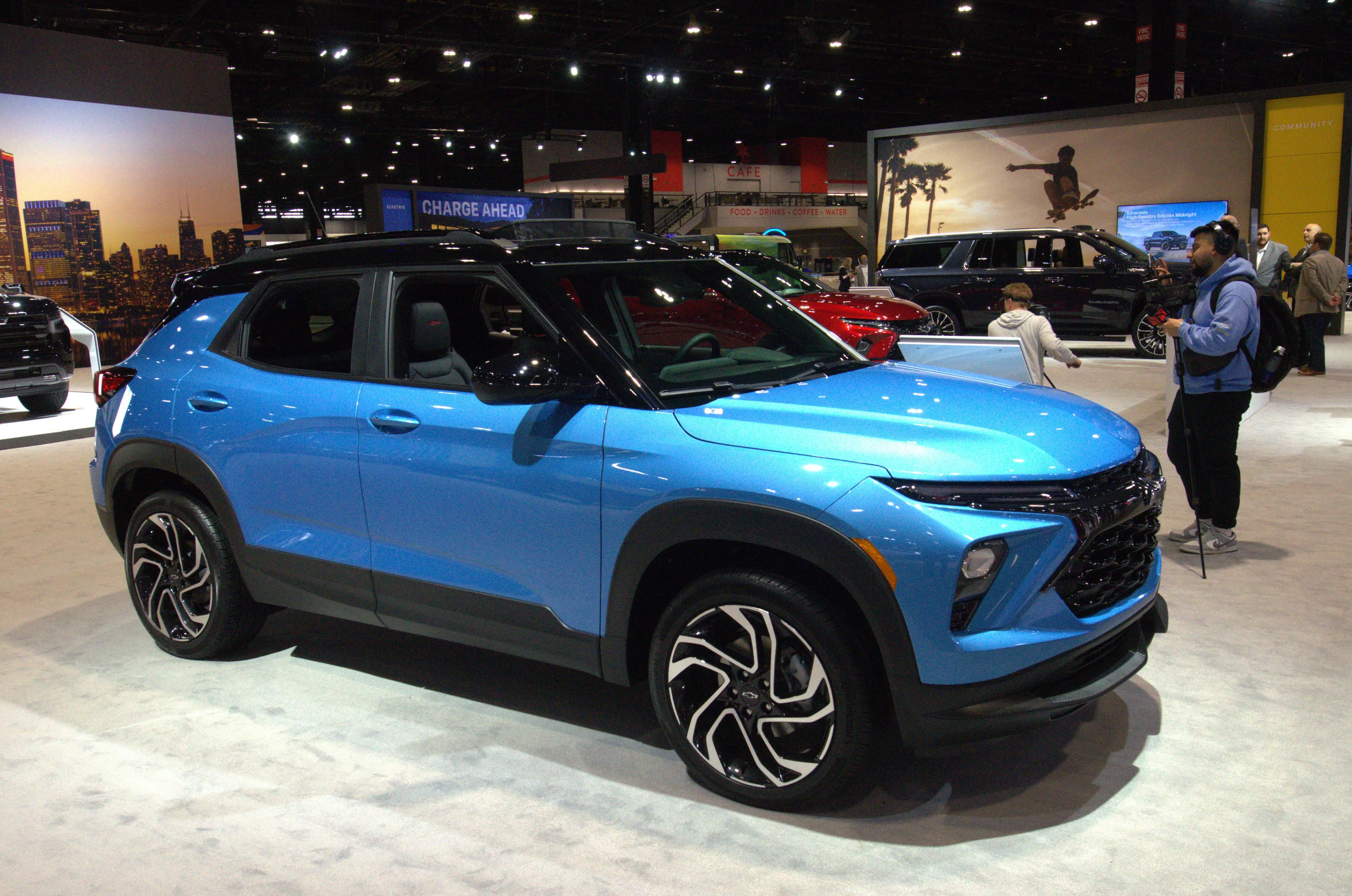 A blue Chevy Trailblazer with a black top is parked on the showroom floor during an auto showcase.