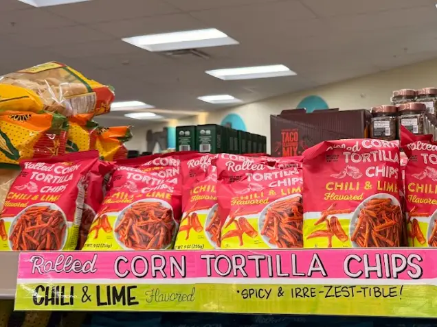 Multiple bags of Trader Joe's chili-and-lime flavored rolled corn tortilla chips sitting on a shelf.