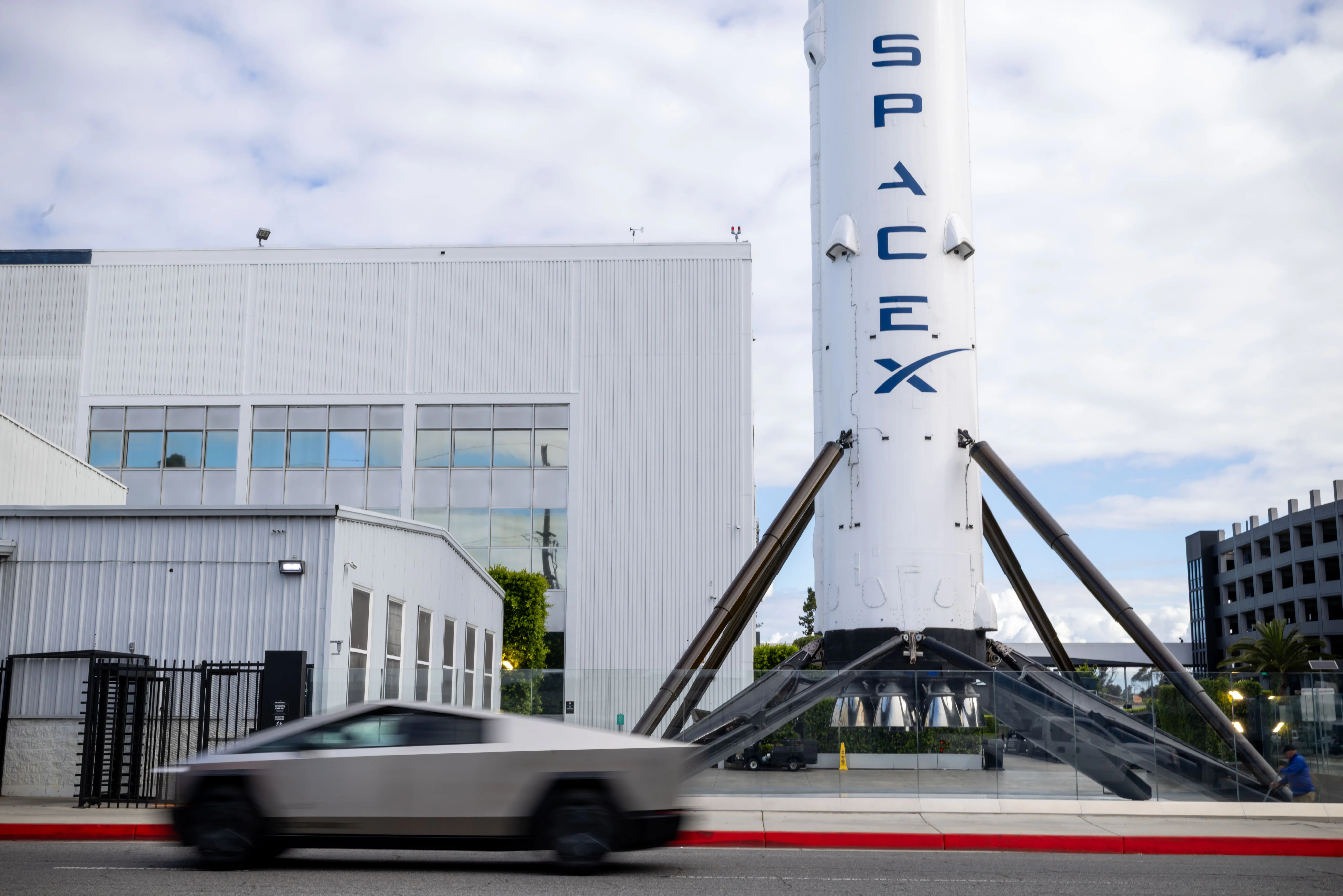 A Cybertruck drives by a SpaceX rocket.