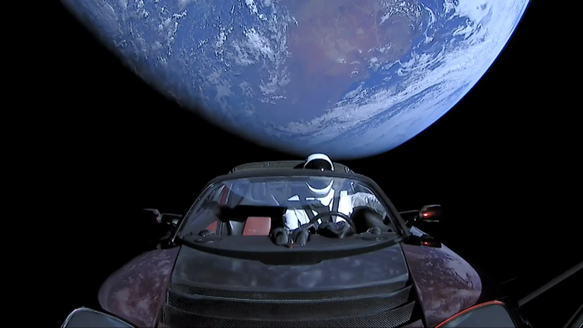A Tesla Roadster, complete with a mannequin in an astronaut suit, orbits the Earth.