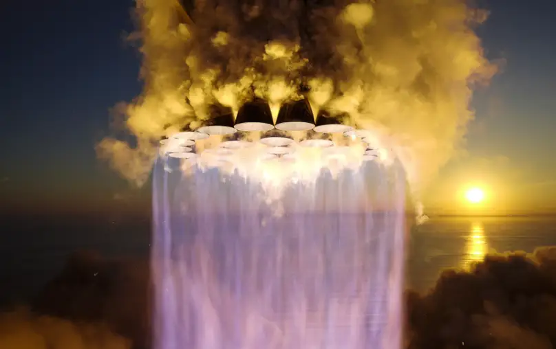 A SpaceX rocket propels upward during a launch at sunset.