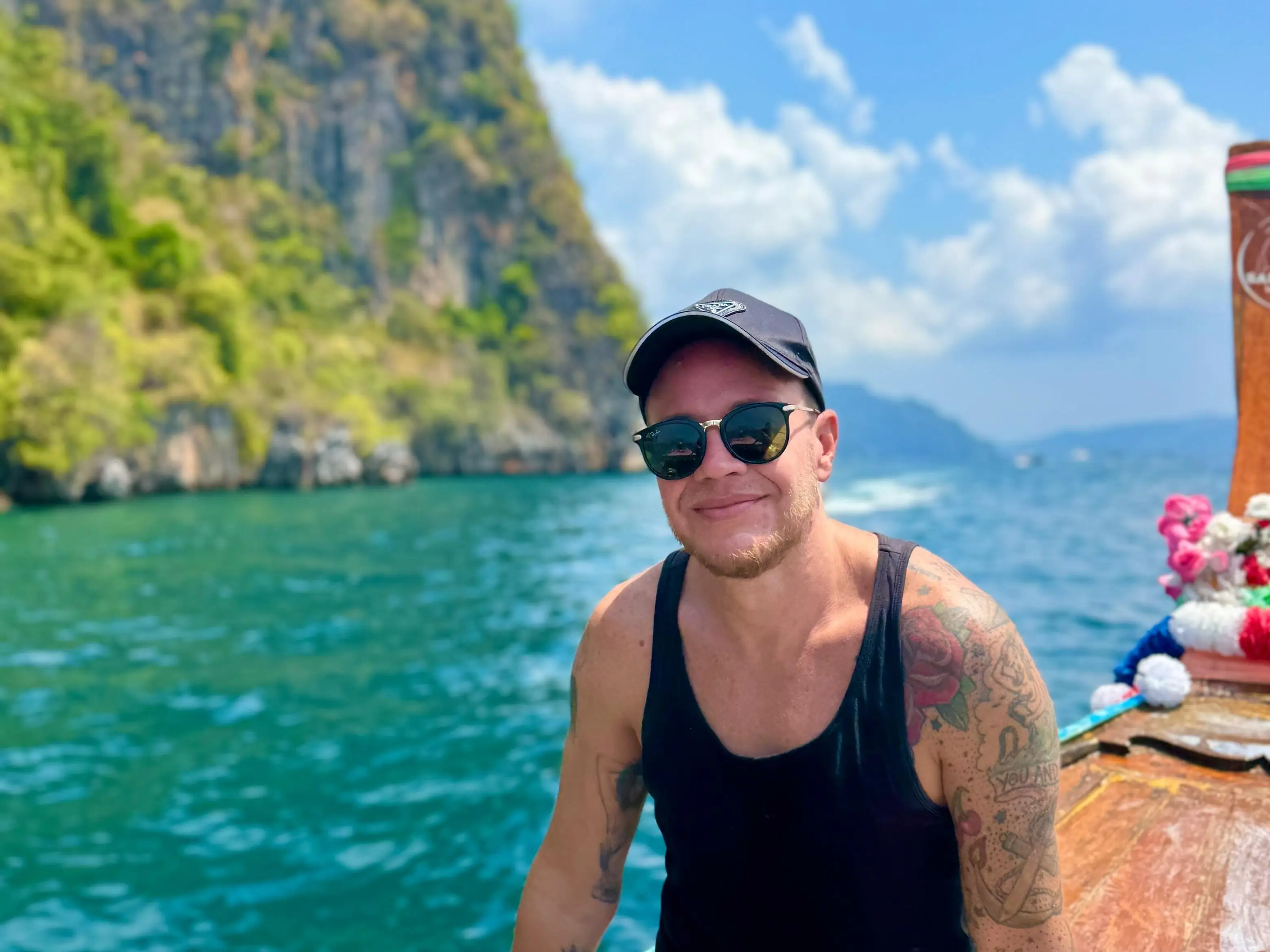A man in sunglasses smiling from a boat in Thailand.