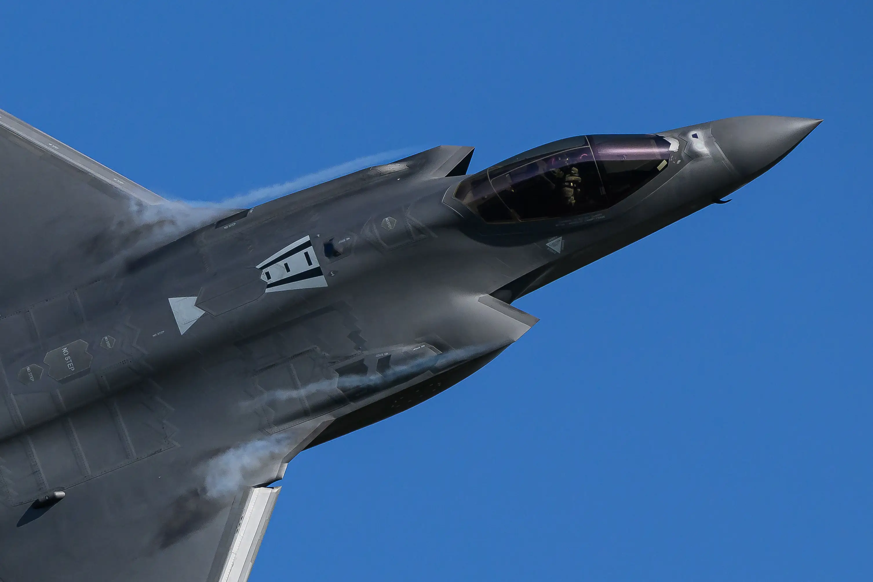 A grey jet on its side in a blue sky