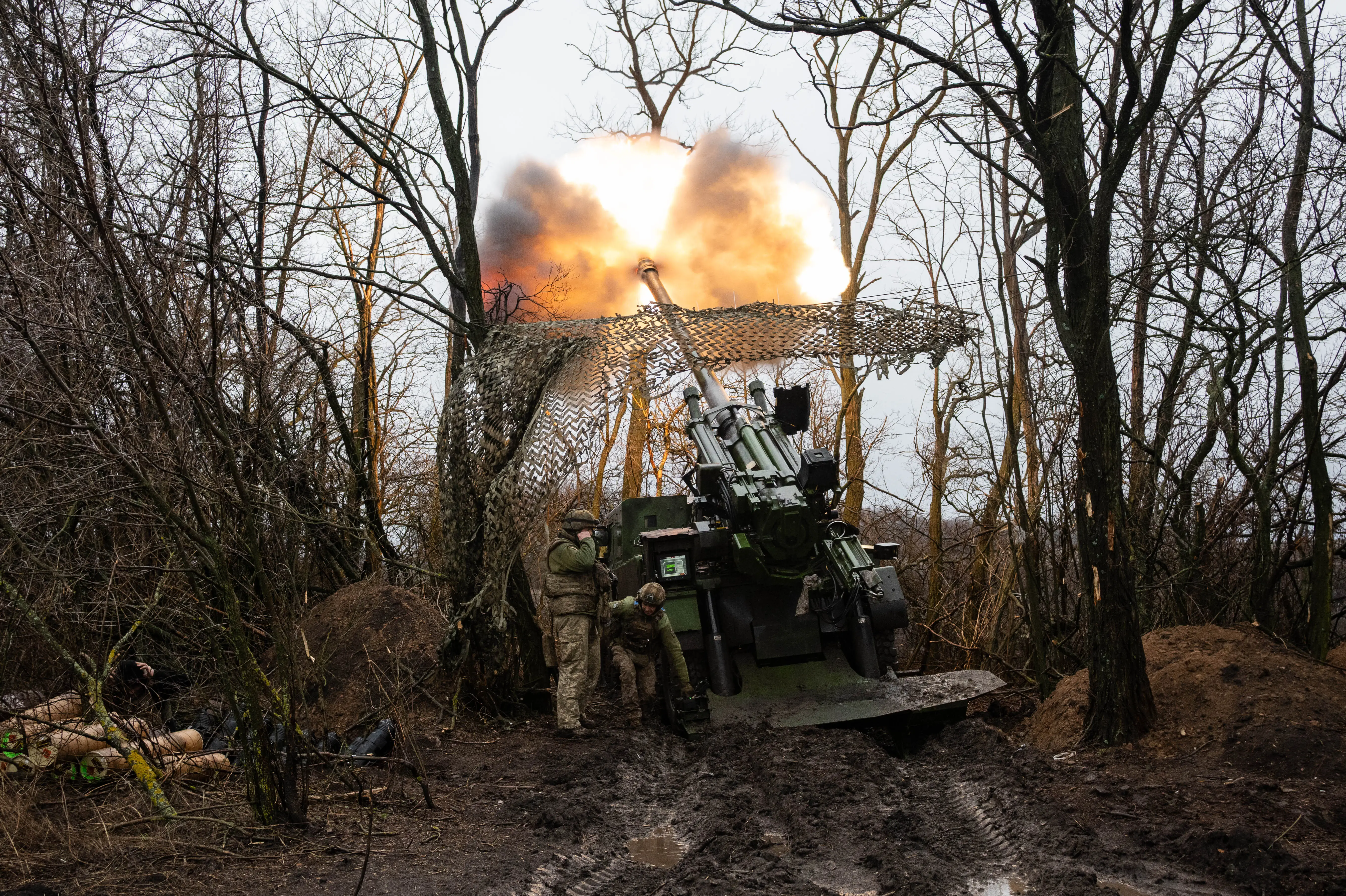 A CAESAR self-propelled howitzer crew of the 148th Artillery Brigade fires toward enemy lines from a concealed position as soldiers nearby watch the sky for hostile FPV drones, near Pokrovsk, Donetsk Region, Ukraine on January 11, 2026.