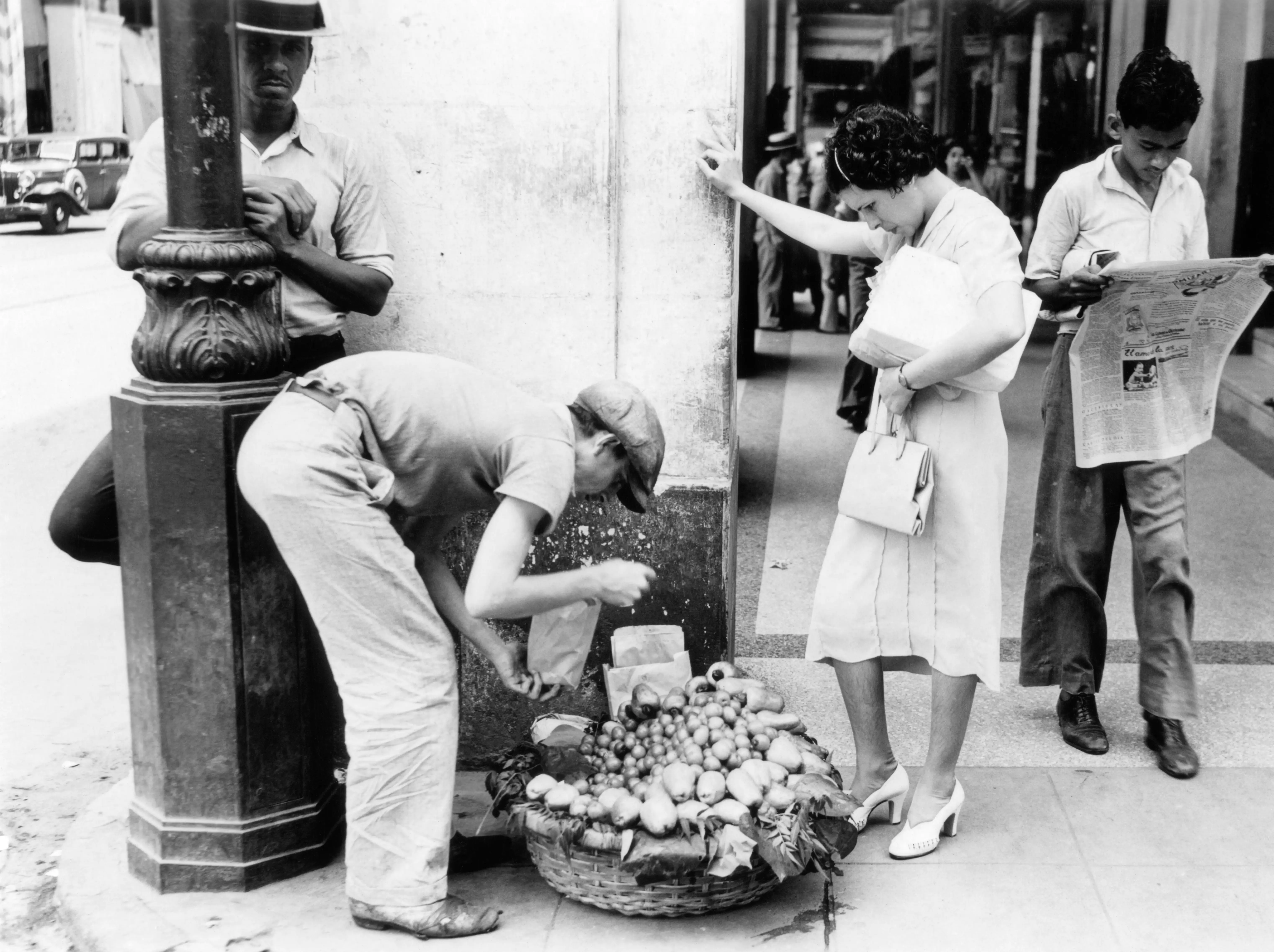 1930s 1940s WOMAN BUYING FRUIT FROM SIDEWALK VENDOR HAVANA CUBA