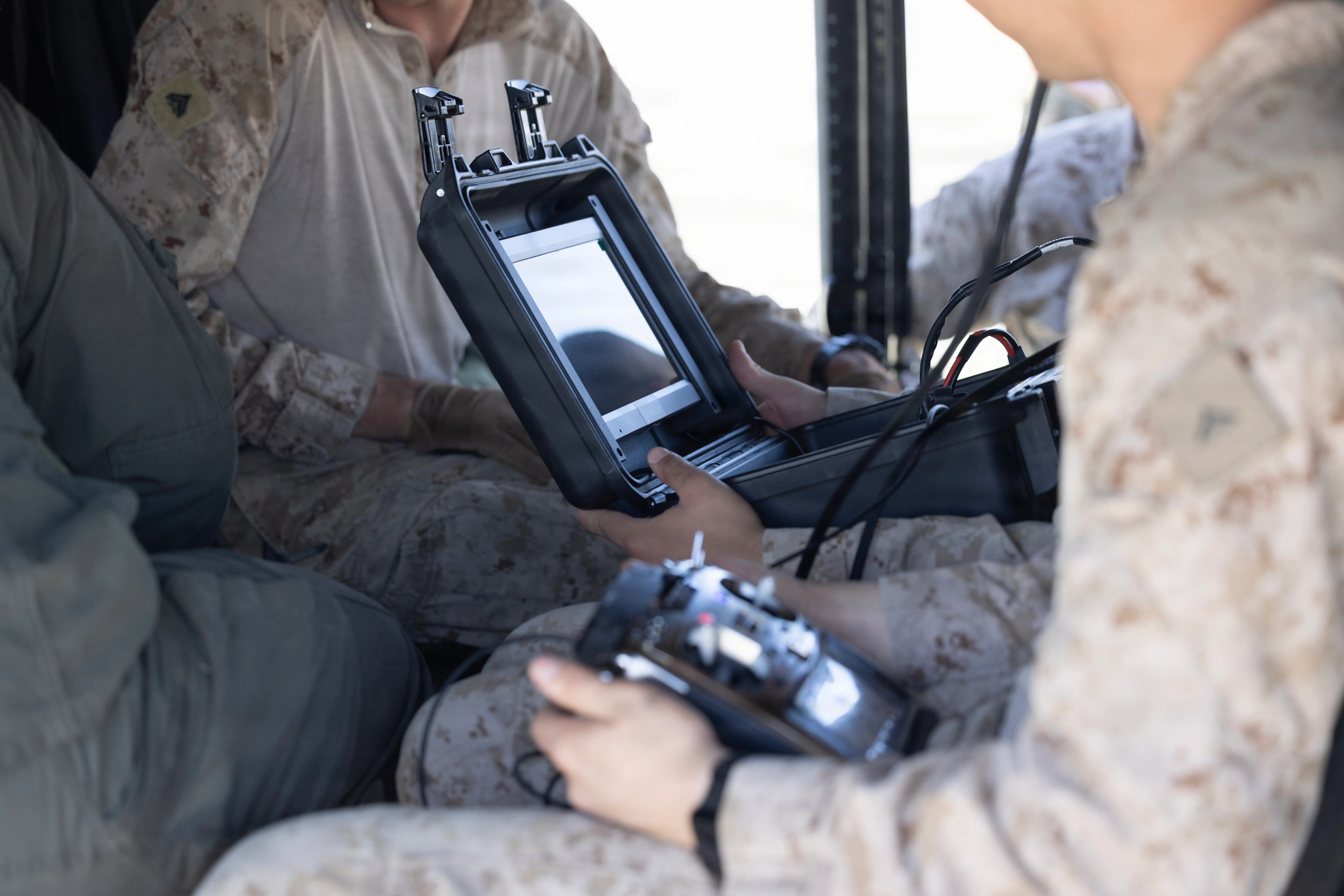 A group of Marines sit inside a helicopter working on a drone monitor.