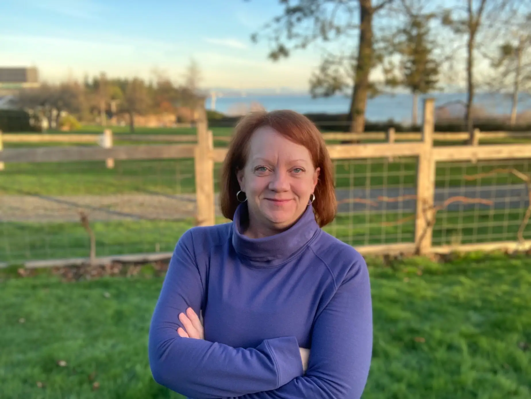 The author wearing a purple turtleneck and crossing her arms.
