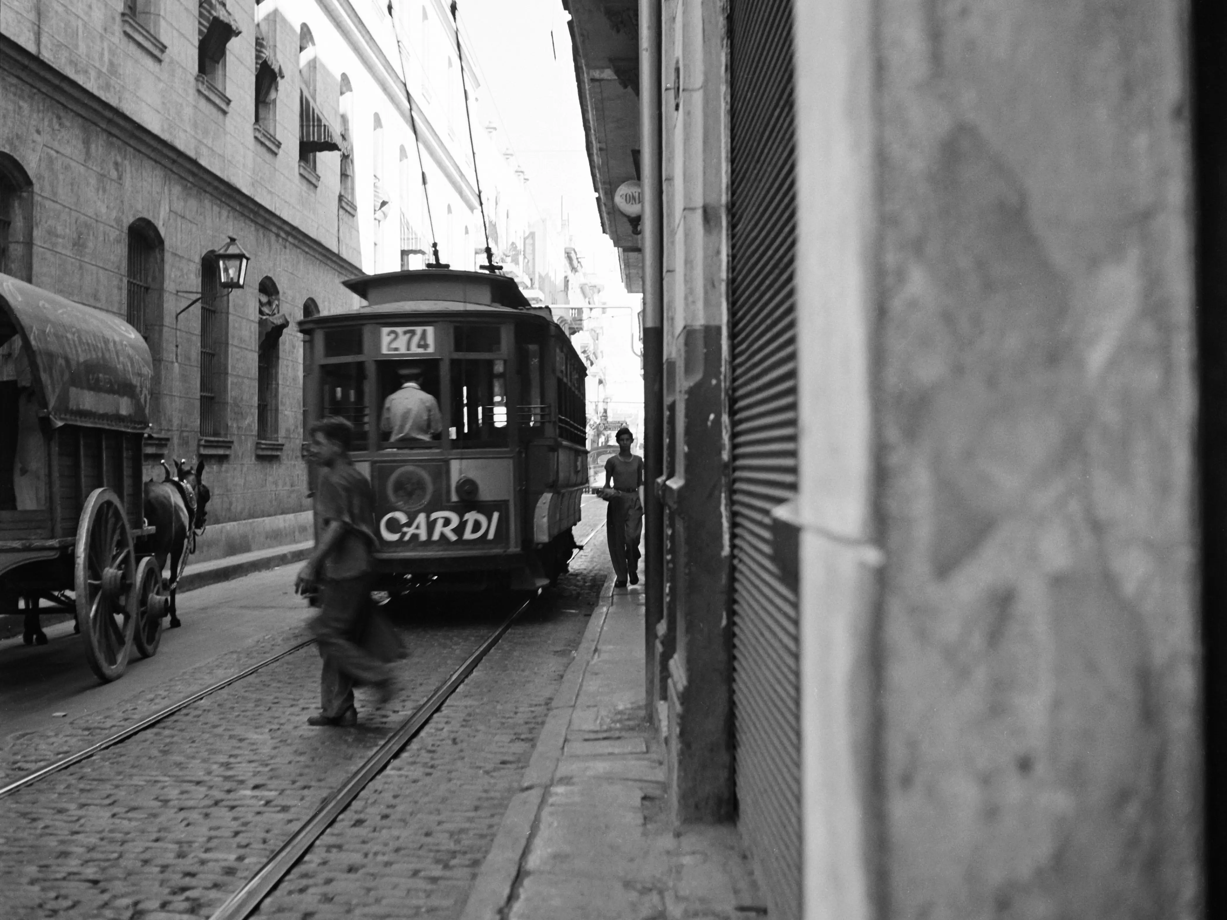 HAVANA, CUBA - JANUARY 1946: A view as a street car passing down a narrow street in Havana, Cuba.