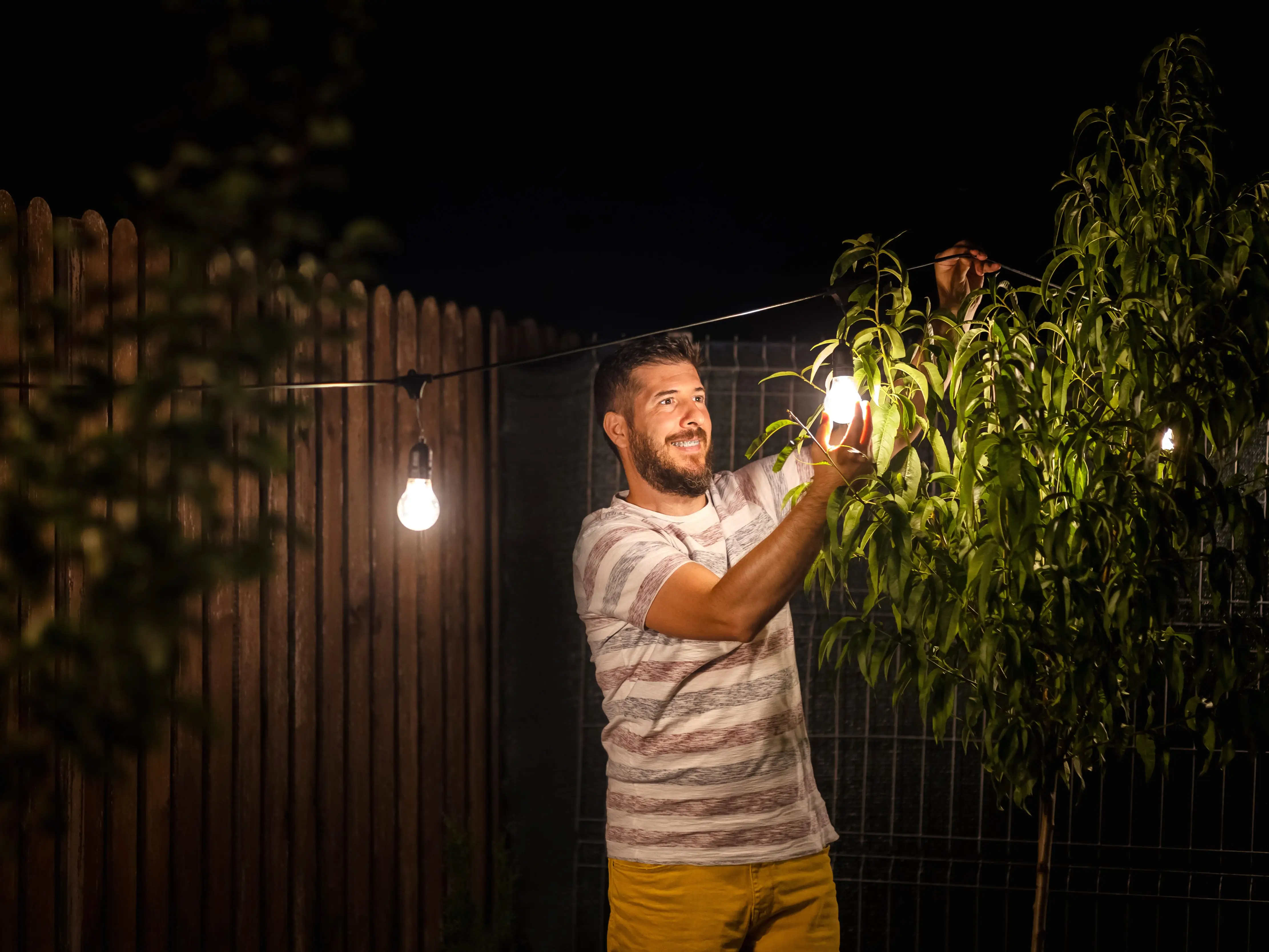 man setting up lights in the backyard