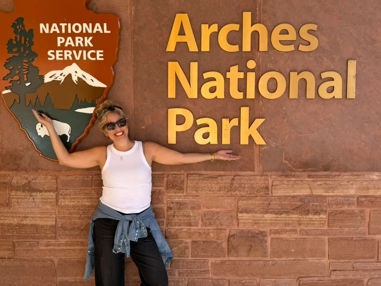 The author in front of a sign that says Arches National Park.
