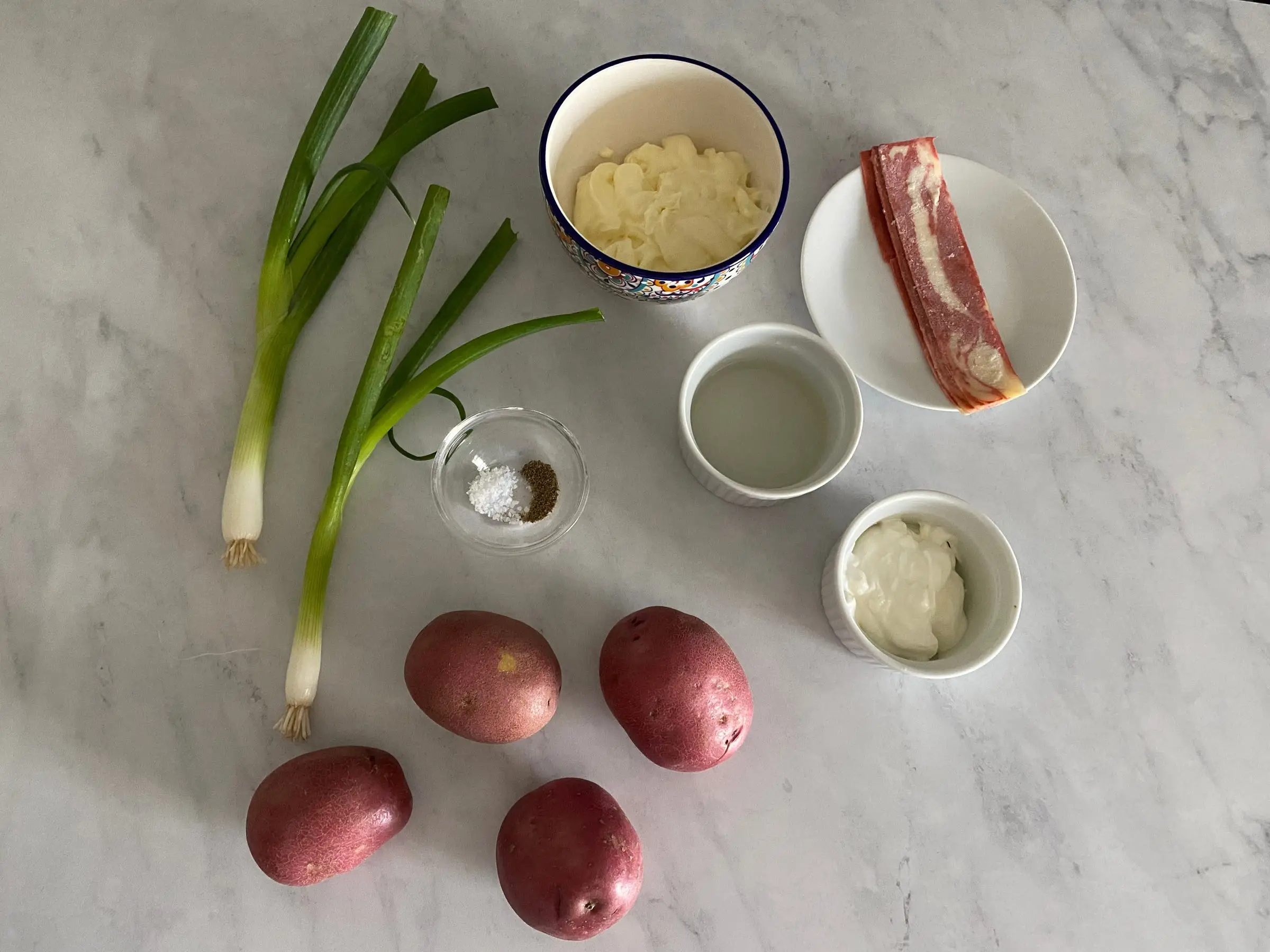 Bacon, green onion, red potatoes and other ingredients on counter
