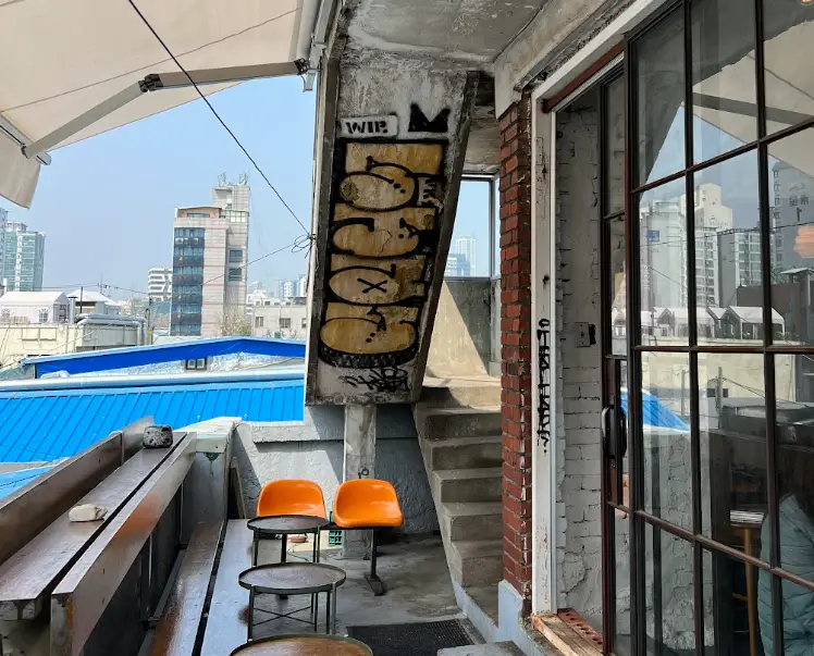 Outdoor seating, with a graffitied wall, outside a restaurant in Mullae-dong, Seoul.