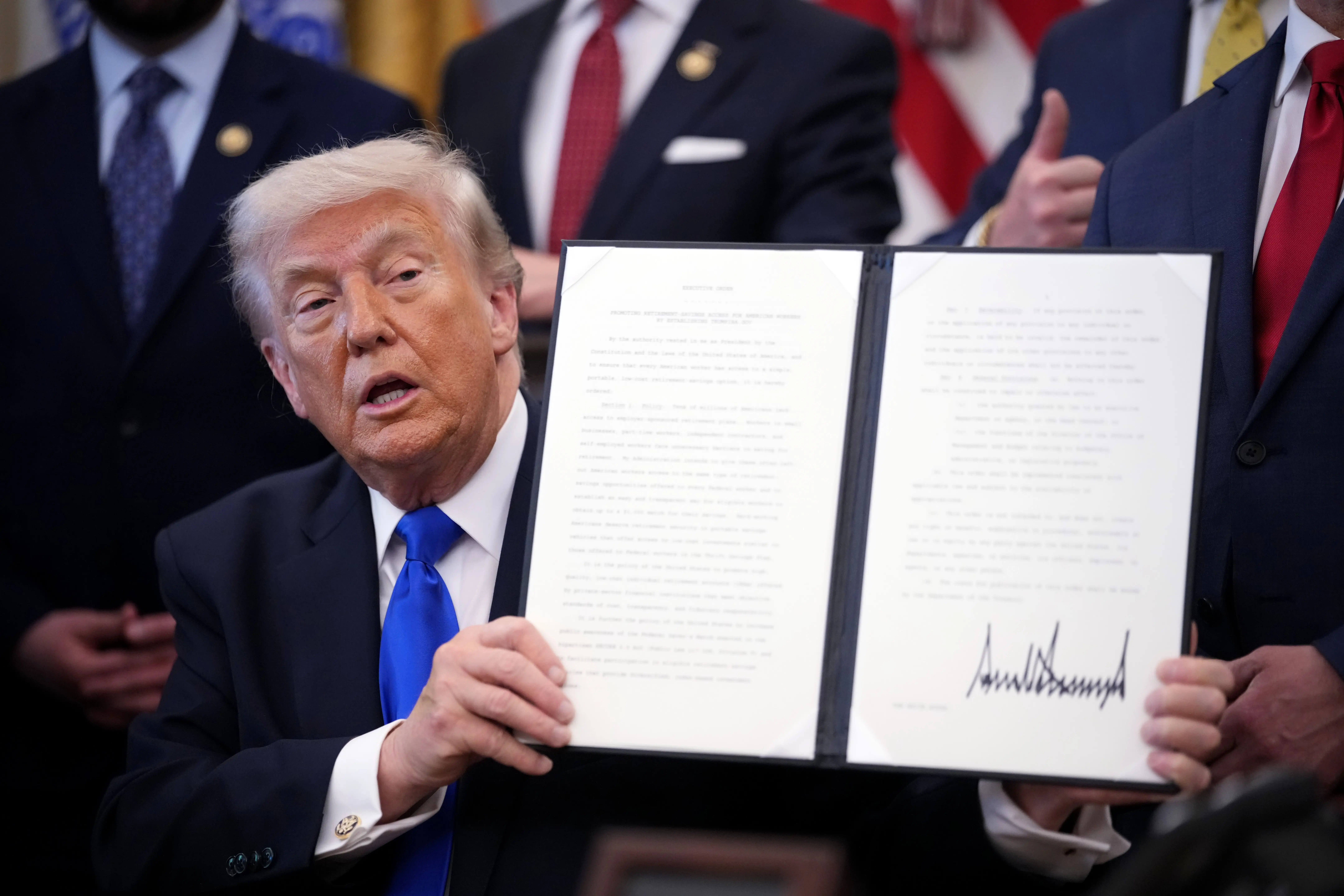 President Donald Trump holds up an executive order in the Oval Office.