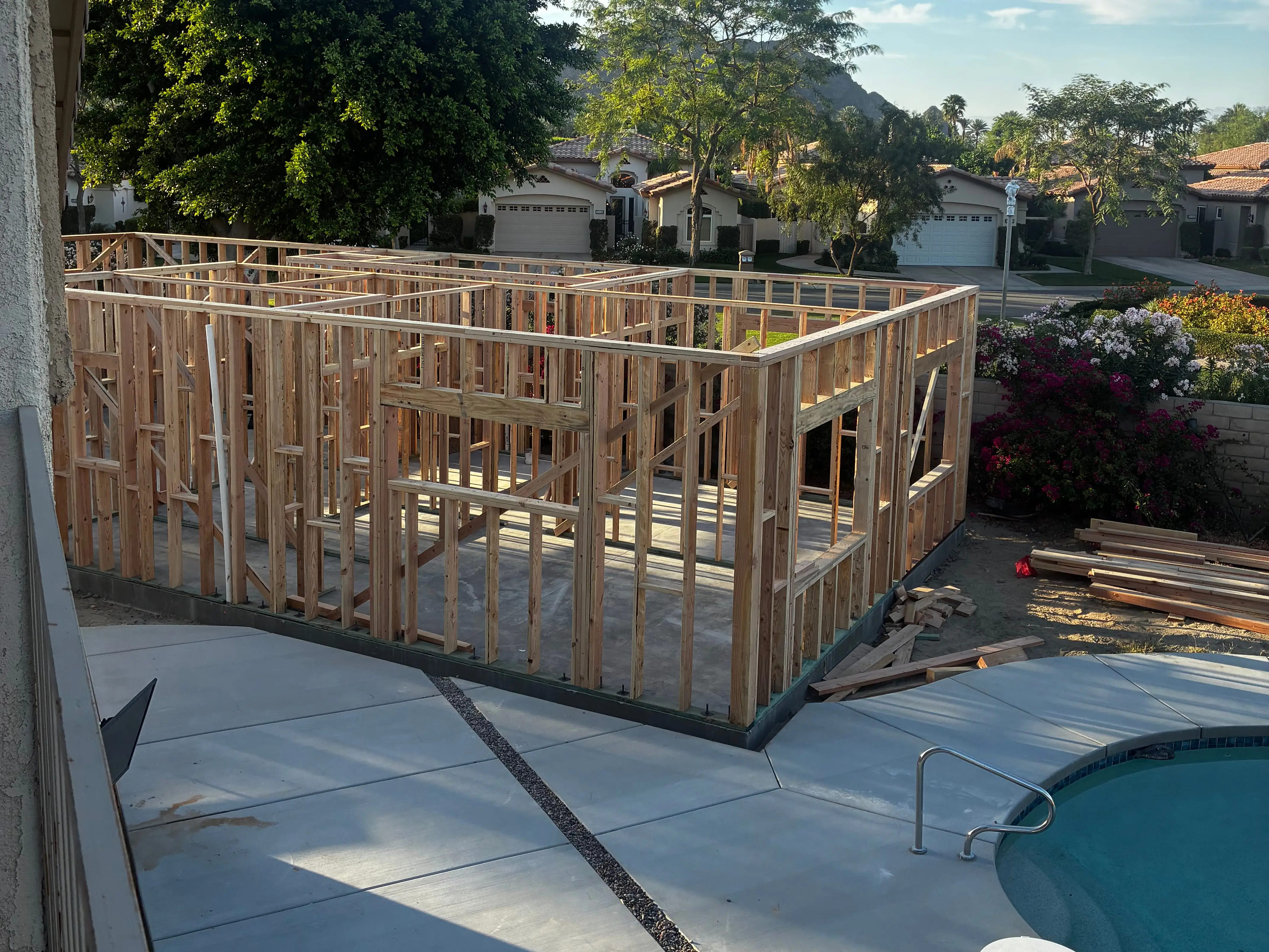 A frame of a small home under construction sitting near a pool.