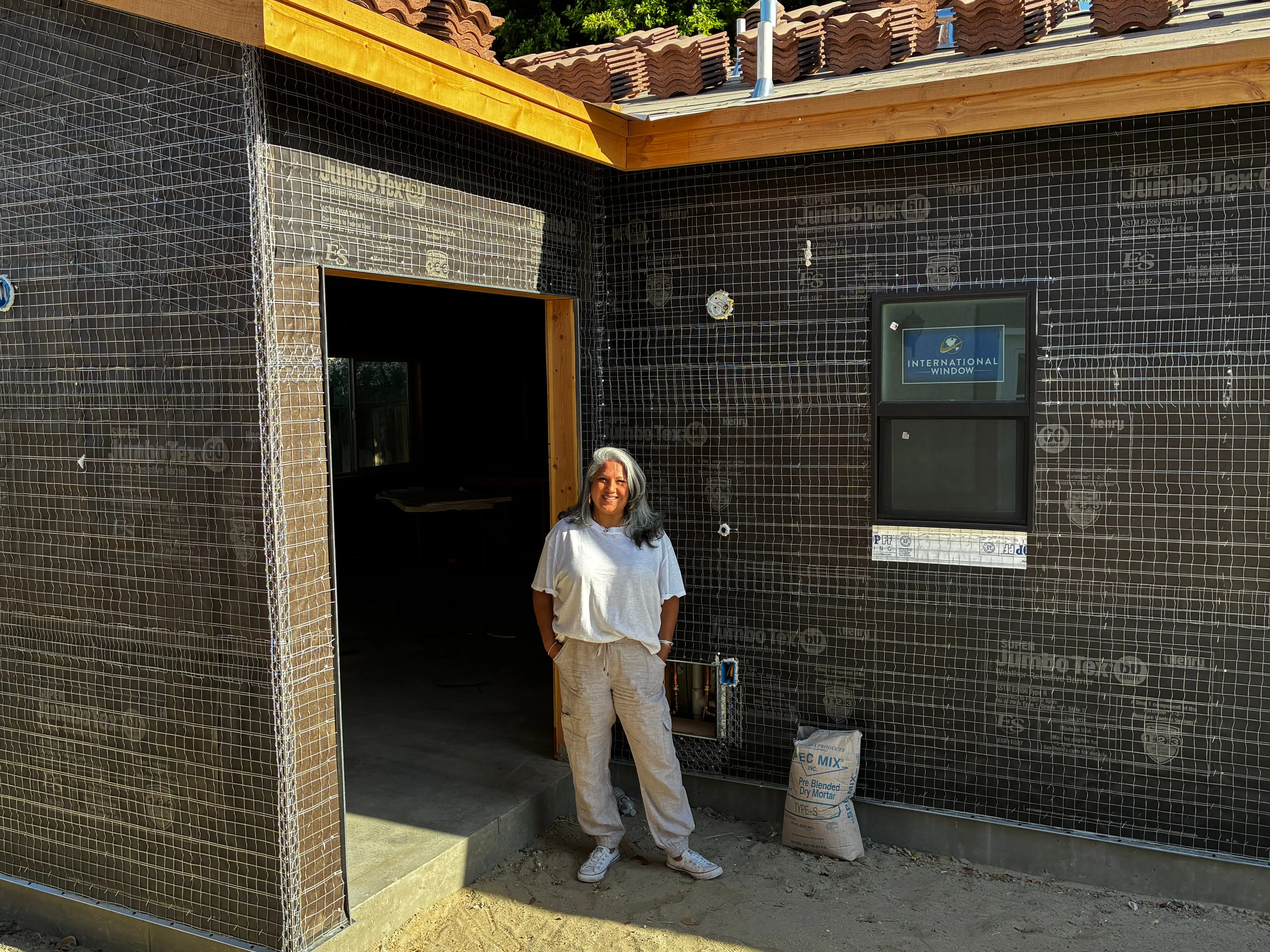 A woman stands in front of a home that's under construction.