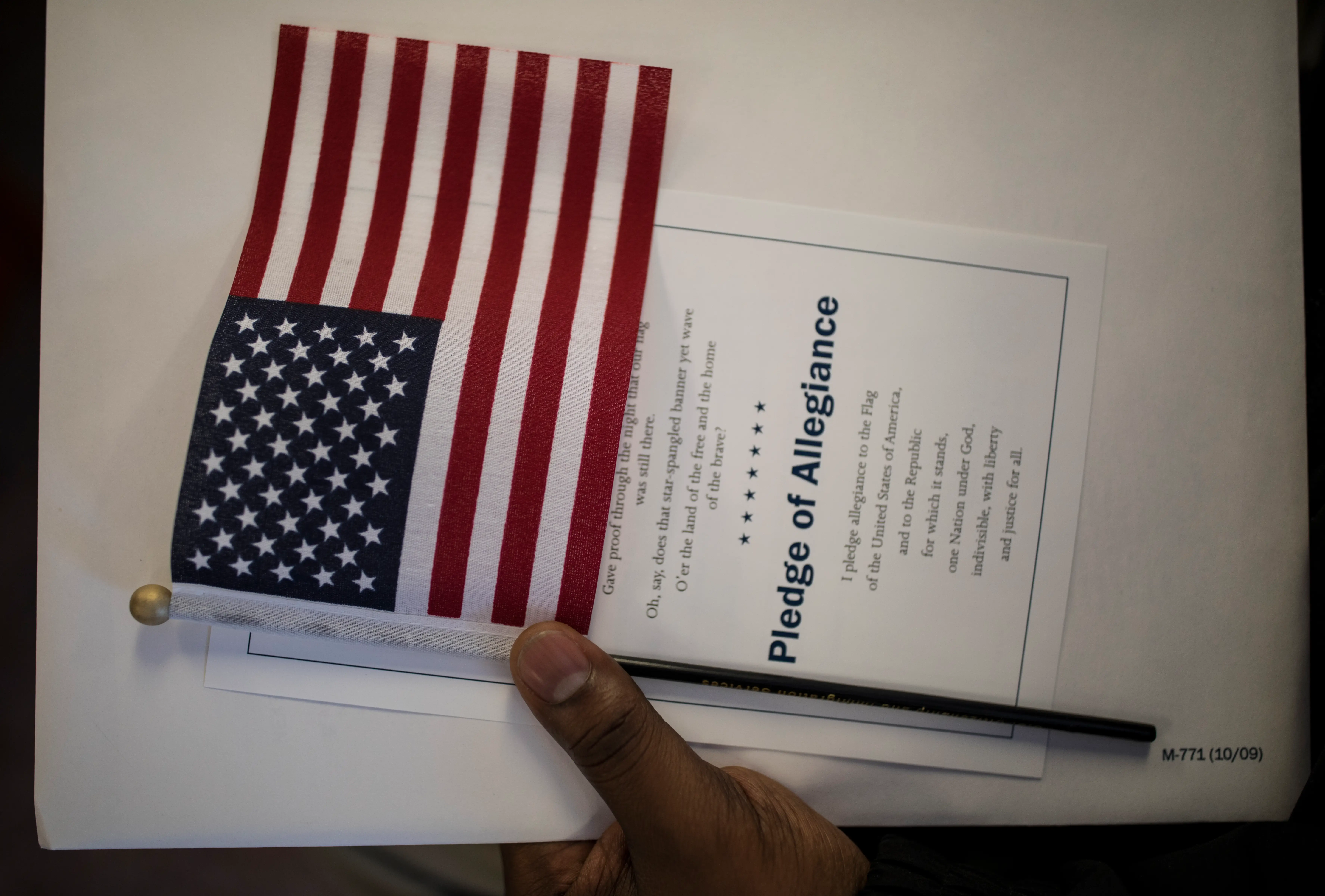 A candidate for US citizenship holds a US flag during a naturalization ceremony for new US citizens.