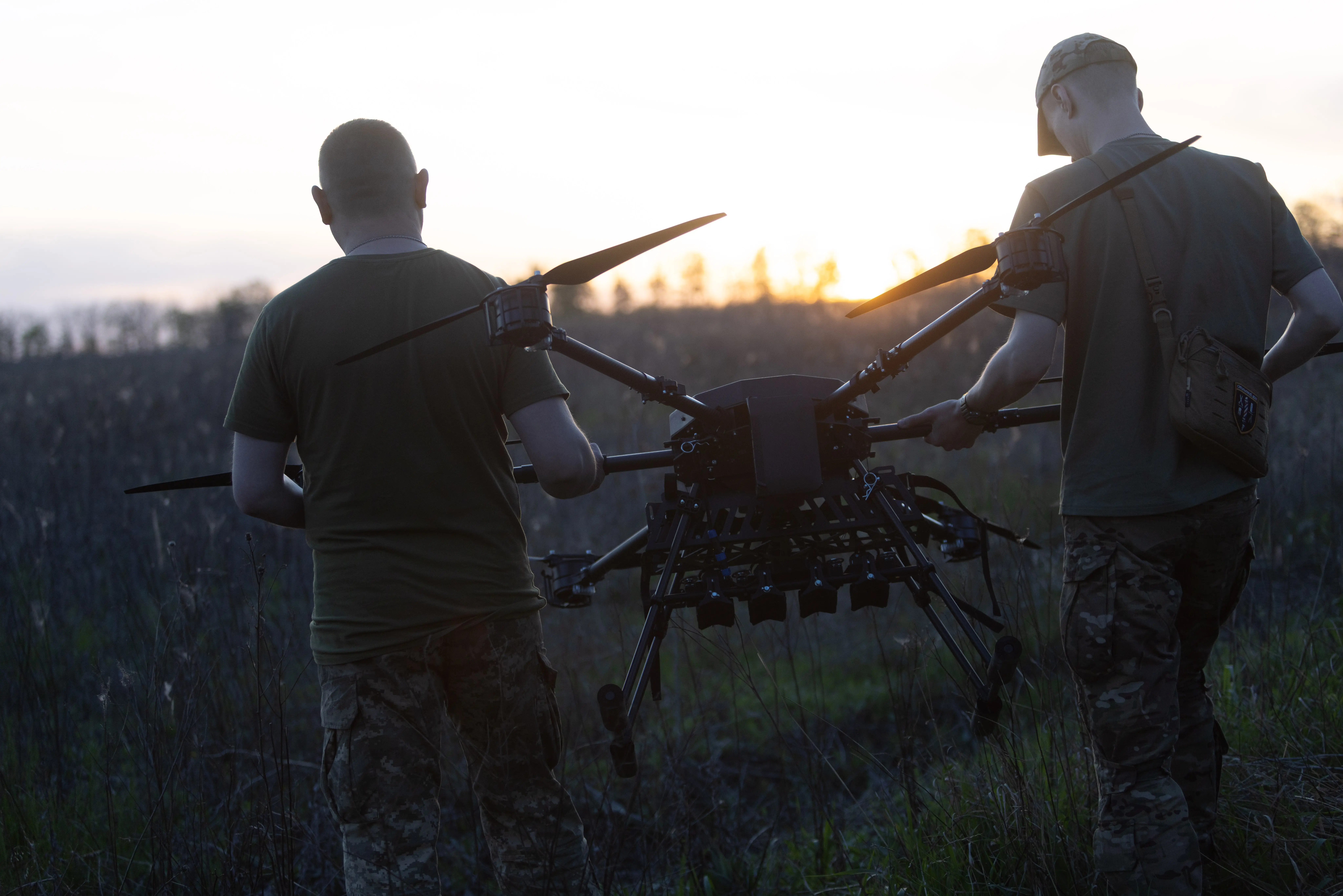 Ukrainian soldiers of the 127th Heavy Mechanized Brigade carry a Heavy Shot UAV across a field in May 2026.