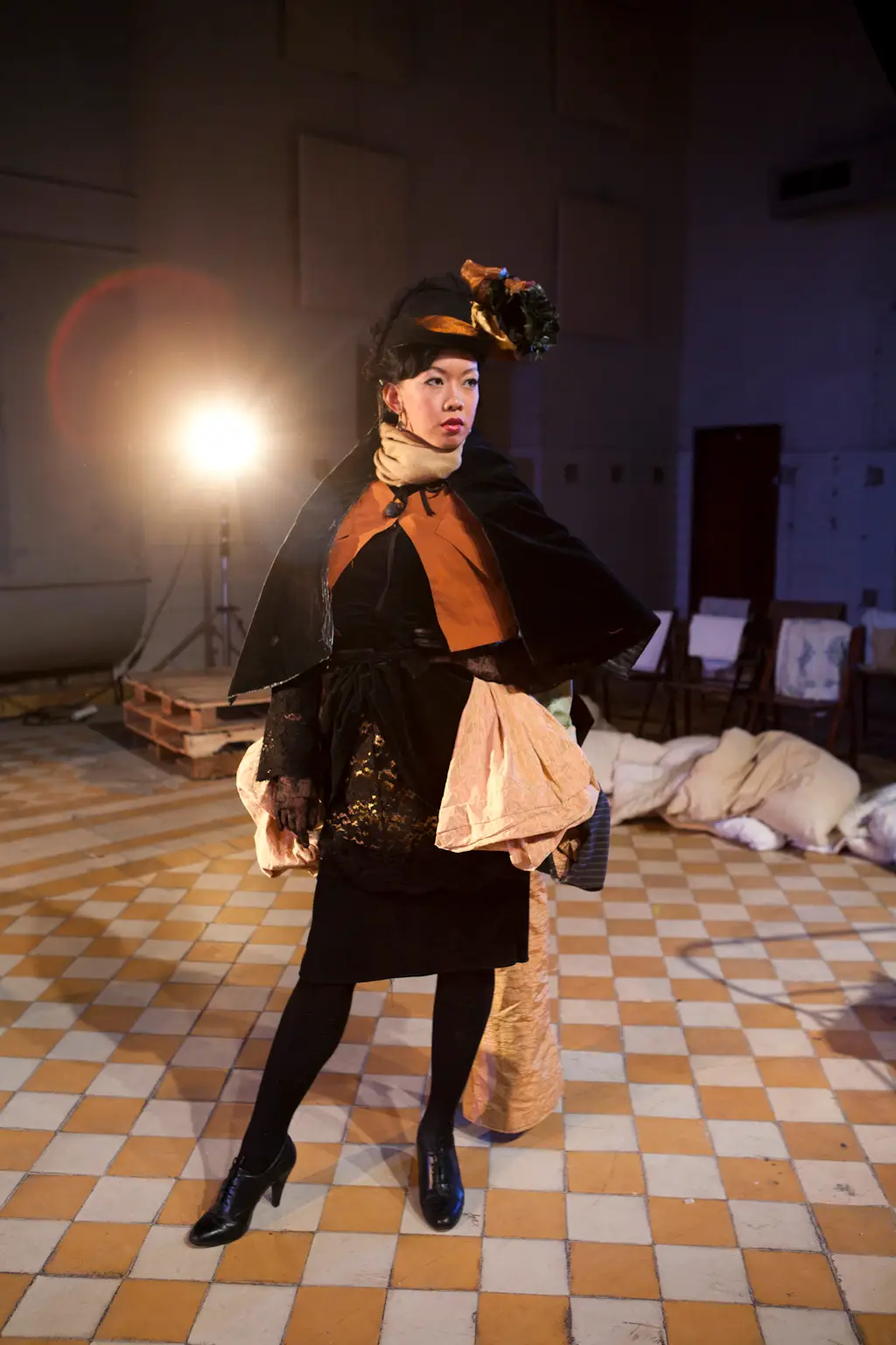 Lily Fen is wearing a stage costume for a performance. The costume is a black dress with a cape and a black hat.