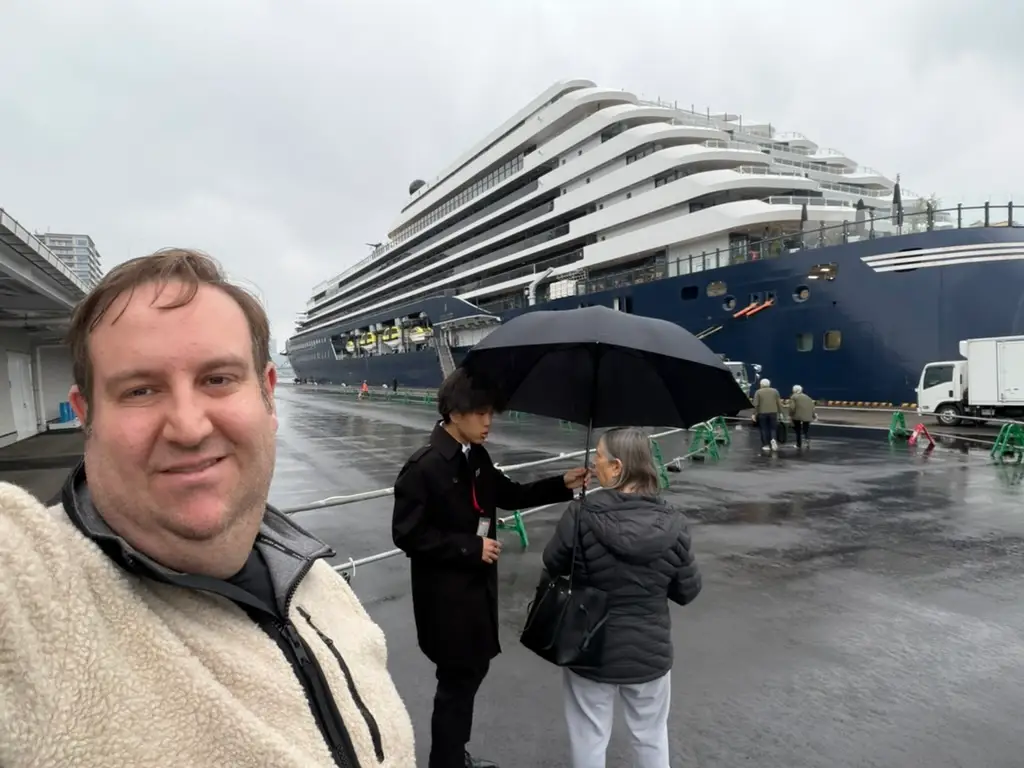 Man smiling near large ship in rain