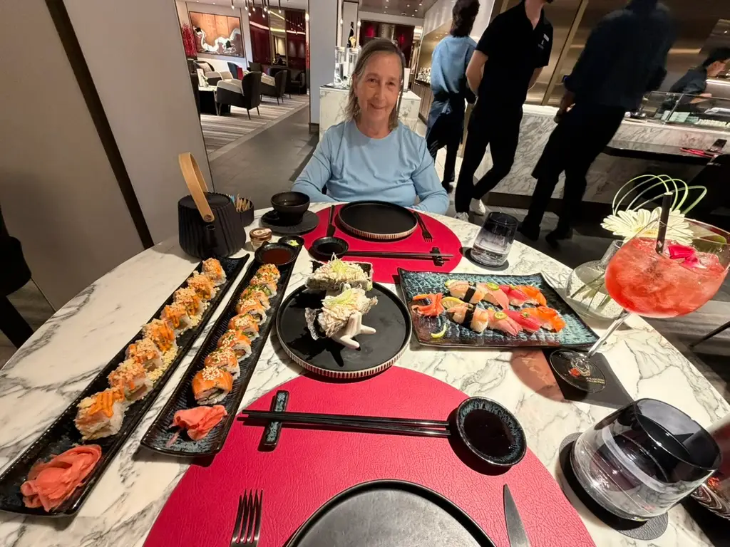 Woman sitting at table filled with sushi, plates