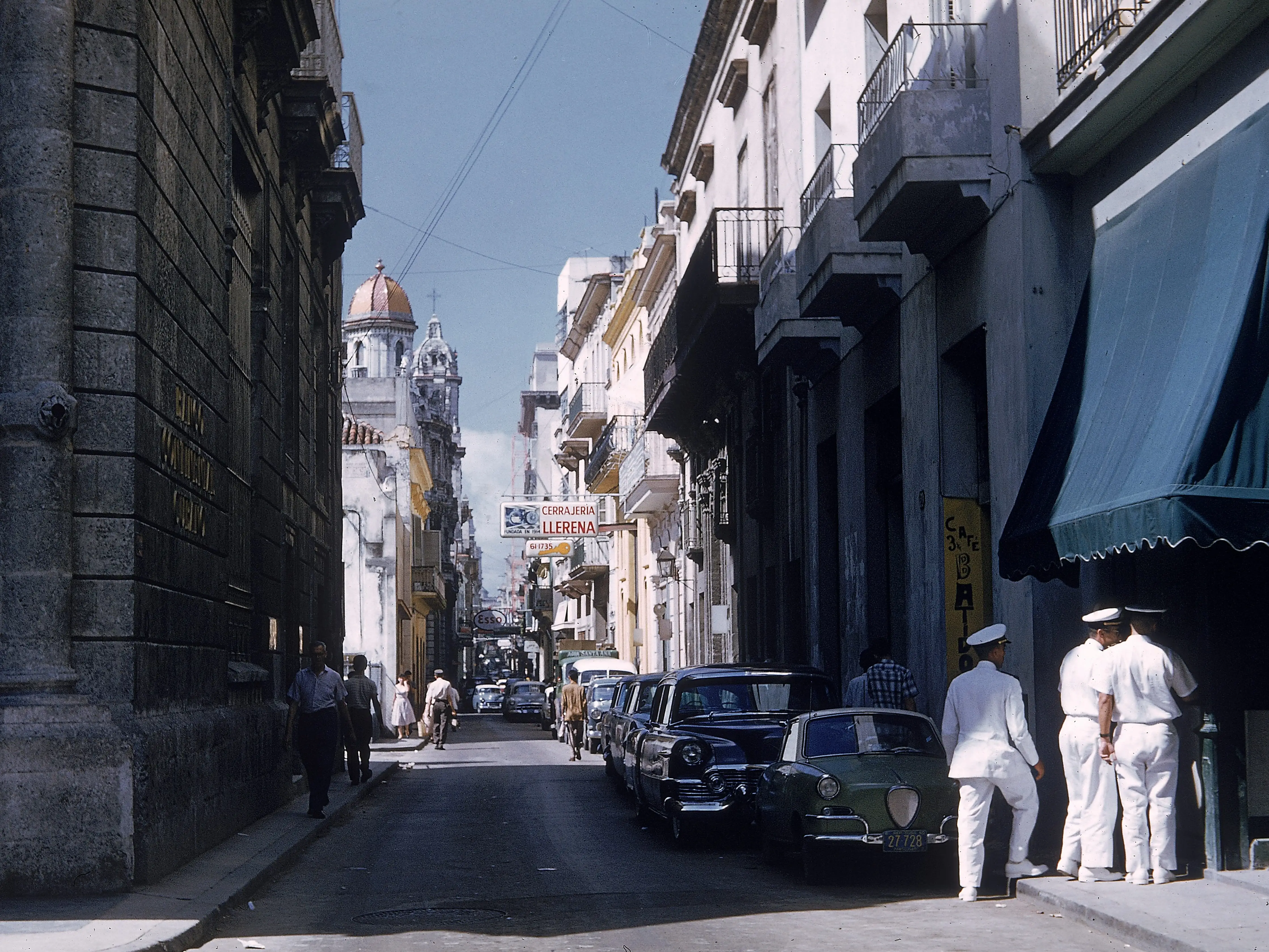 A group of sailors stand outside a cafe at the end of a narrow street in Old Havana, Cuba,